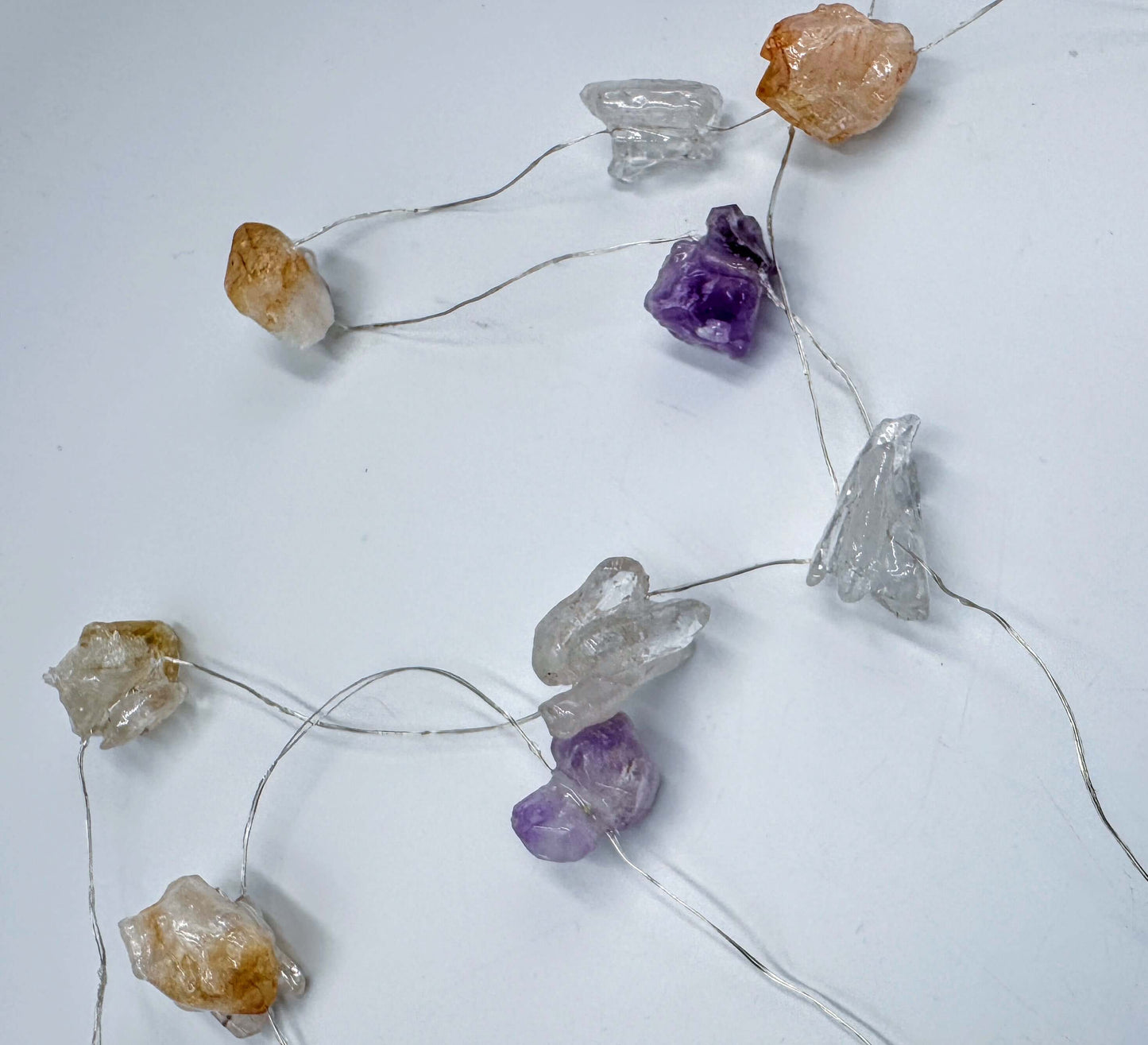 Crystal fairy lights featuring amethyst and clear quartz, glowing with cool white light, 3 meters long with 8 flash settings.