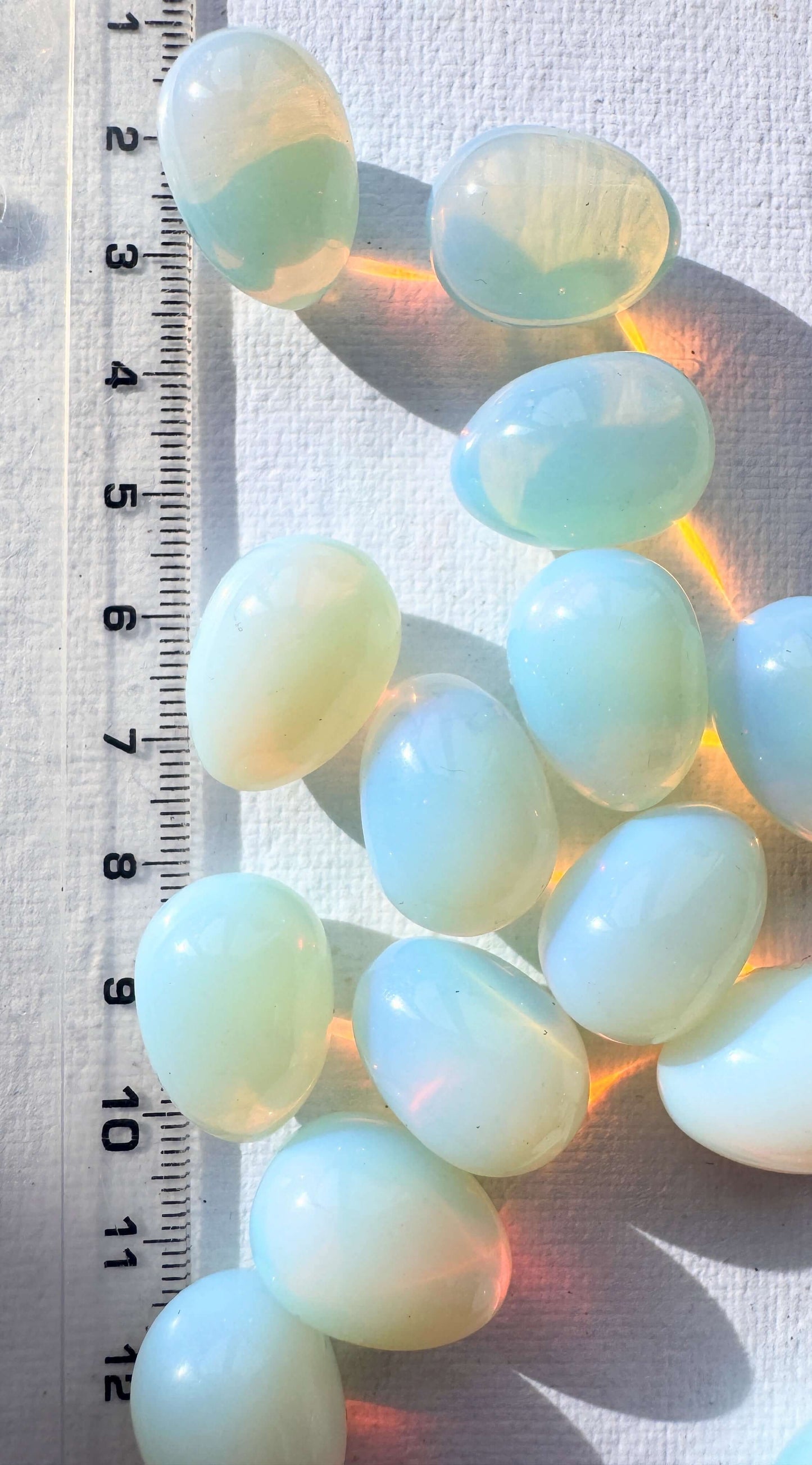 Mini opalite eggs arranged on a white surface, showcasing their smooth, polished finish and soft glowing colors.
