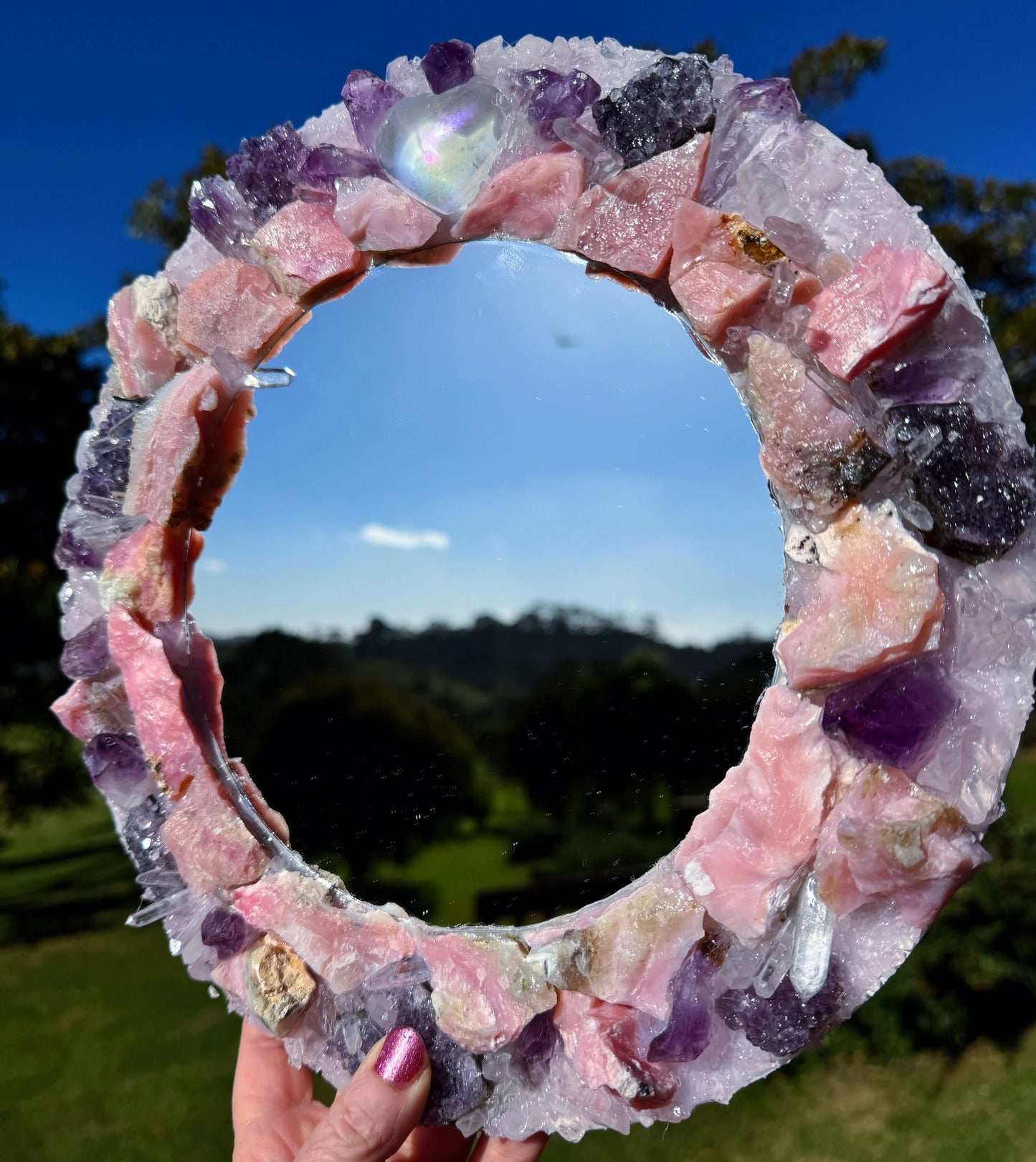 Angel Aura Love Crystal Mirror 28cm with Pink Aura Quartz, Rose Quartz, Amethyst, and Clear Quartz in a luminous outdoor setting
