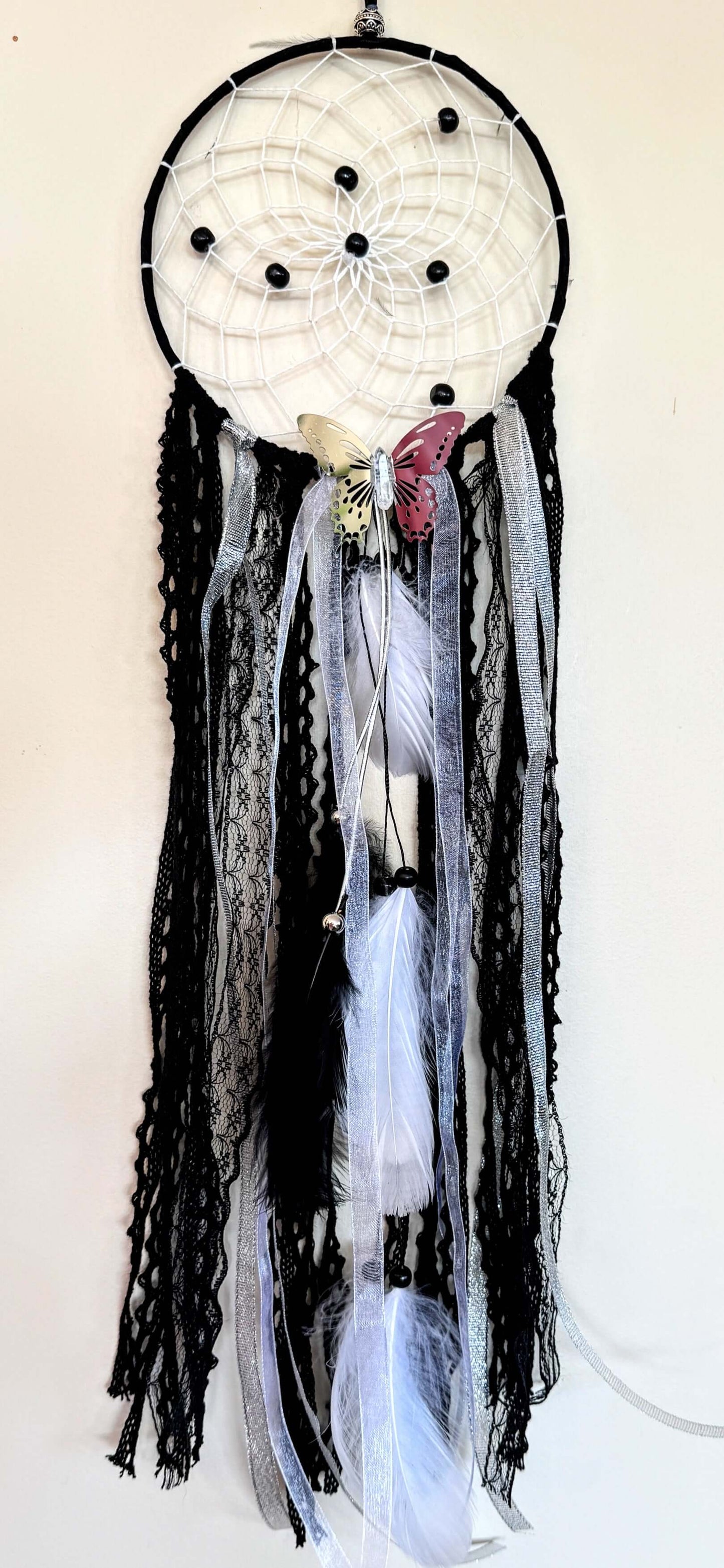 Black dream catcher featuring lace, ribbons, and feather accents, symbolizing grounded energy and protection.
