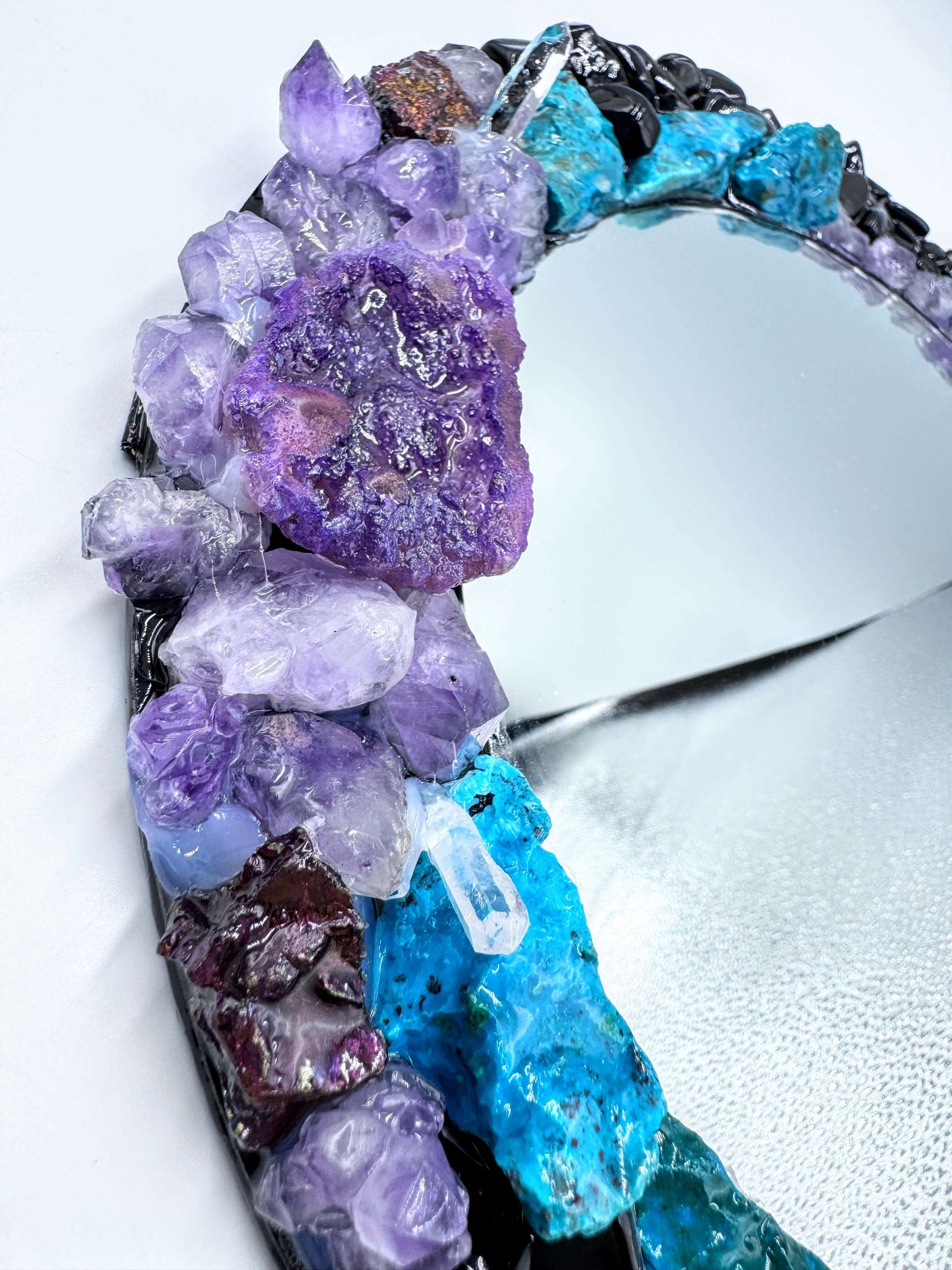 Handmade crystal mirror with gemstone border reflecting natural light