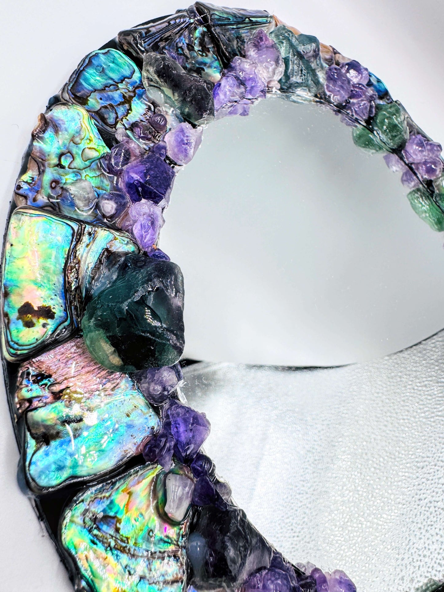 Handmade crystal mirror with gemstone border reflecting natural light