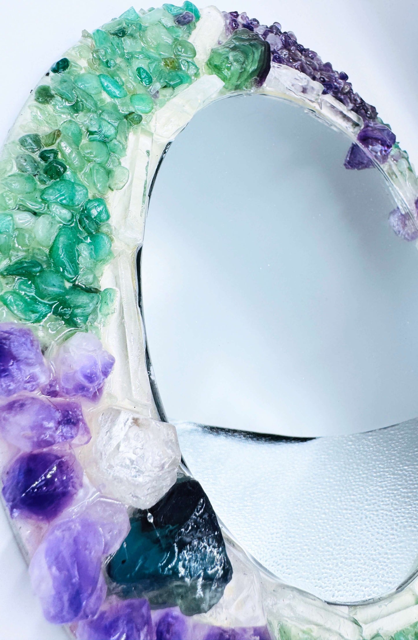Handmade crystal mirror with gemstone border reflecting natural light