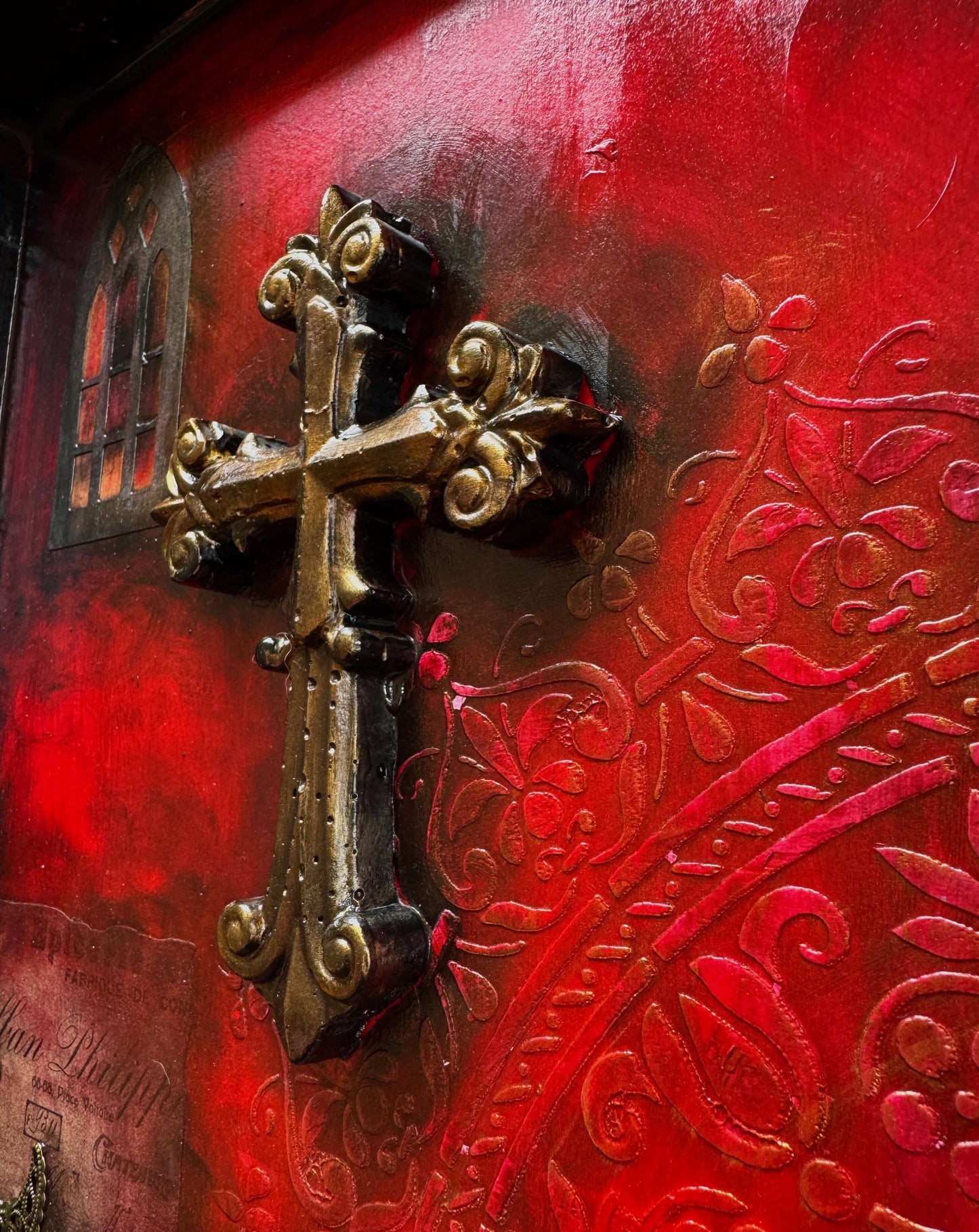 Close-up of a gothic cross on a deep crimson background in a mixed-media shadow box. Crystal art feature.