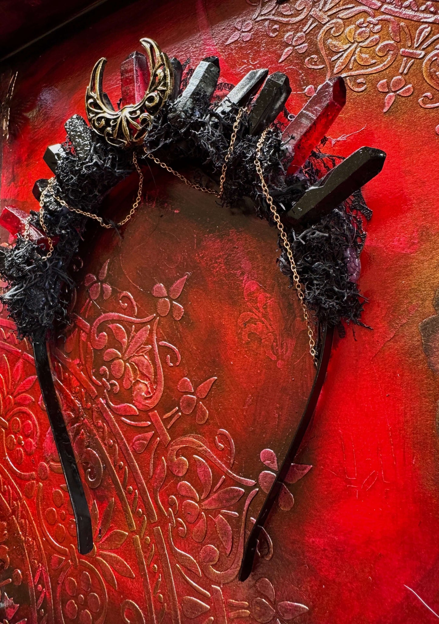 Crimson Thorn Crown showcasing gothic art with crystal points and antique bronze detailing against a textured red background.
