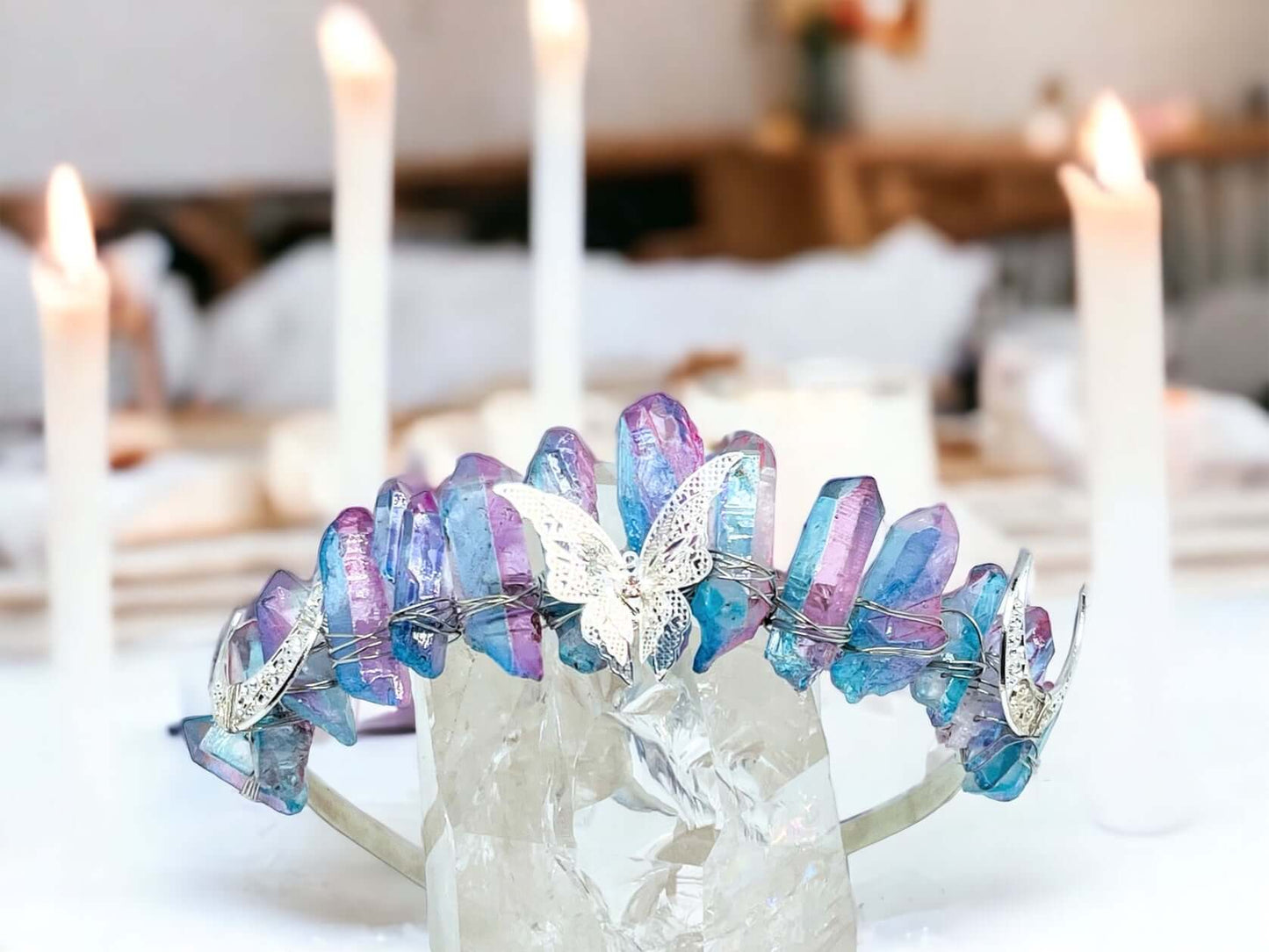 Crystal crown tiara on white surface with candles in background.