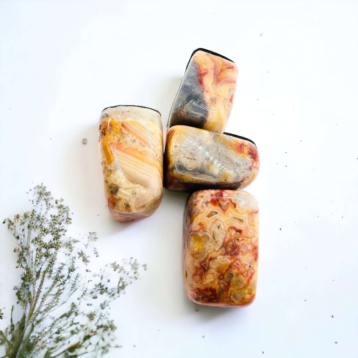 Crazy lace agate tumbled stones on white surface.