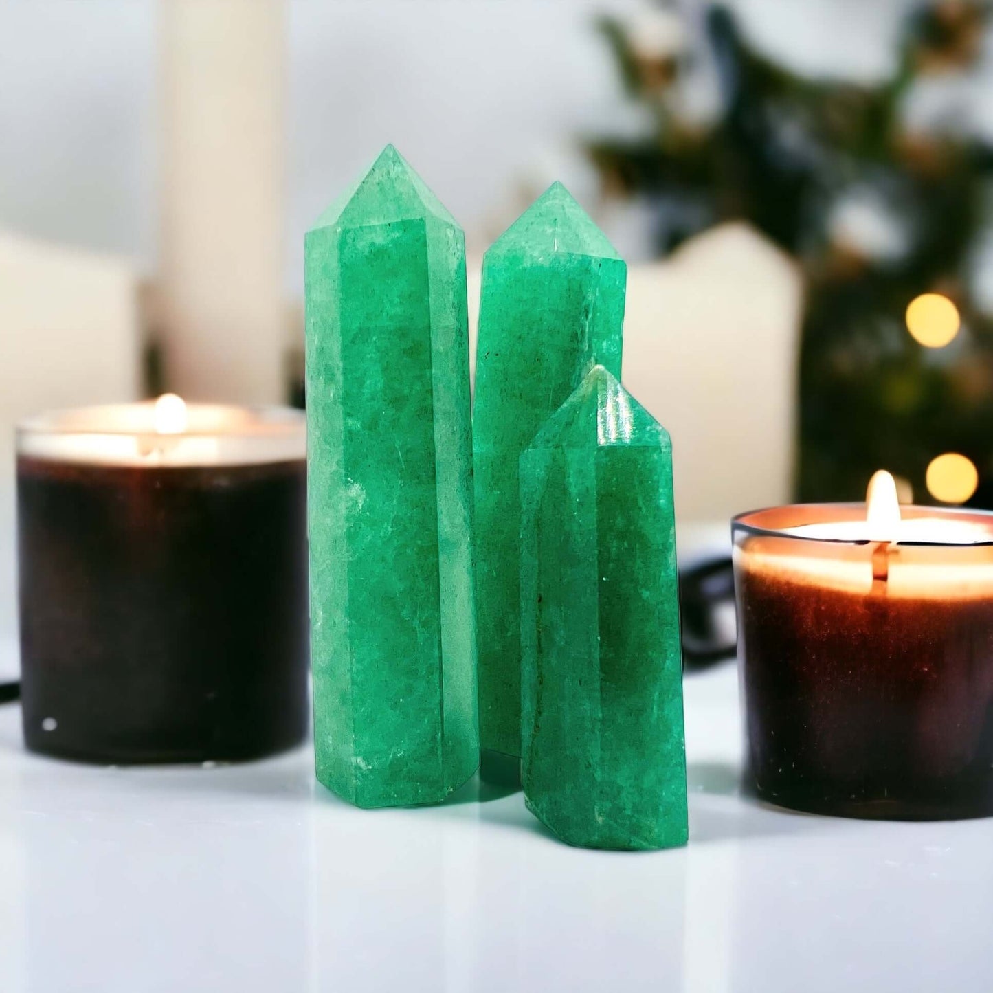Green strawberry quartz points on white bench with candles.
