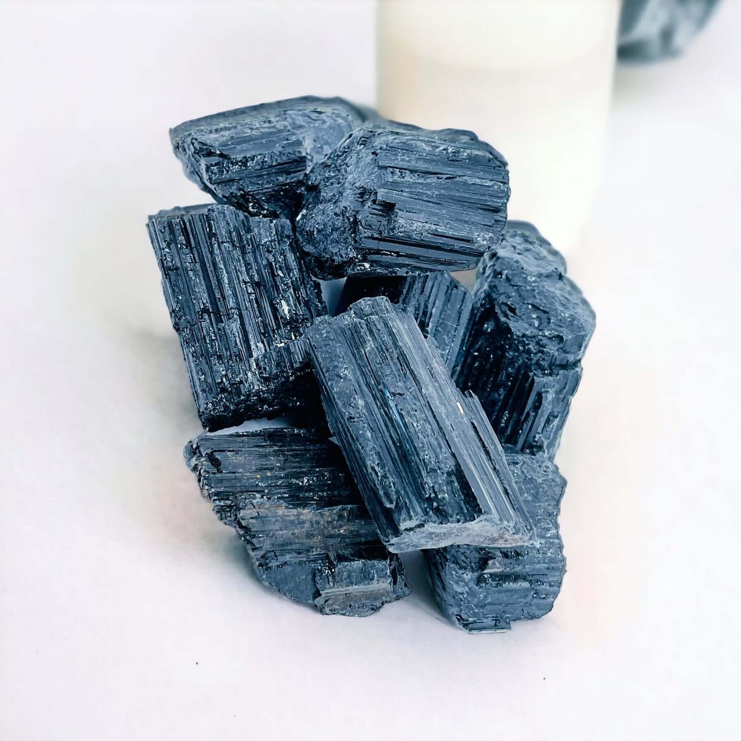 Several black tourmaline pieces on white surface.