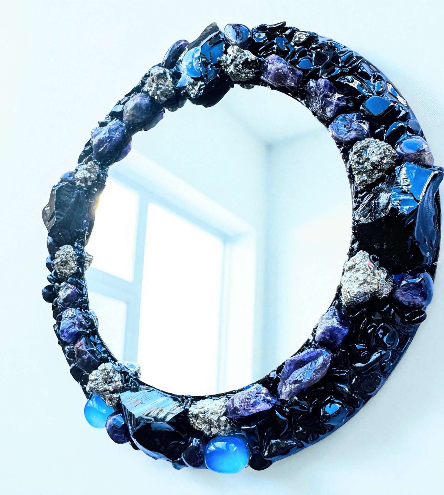 Handmade crystal mirror with gemstone border reflecting natural light