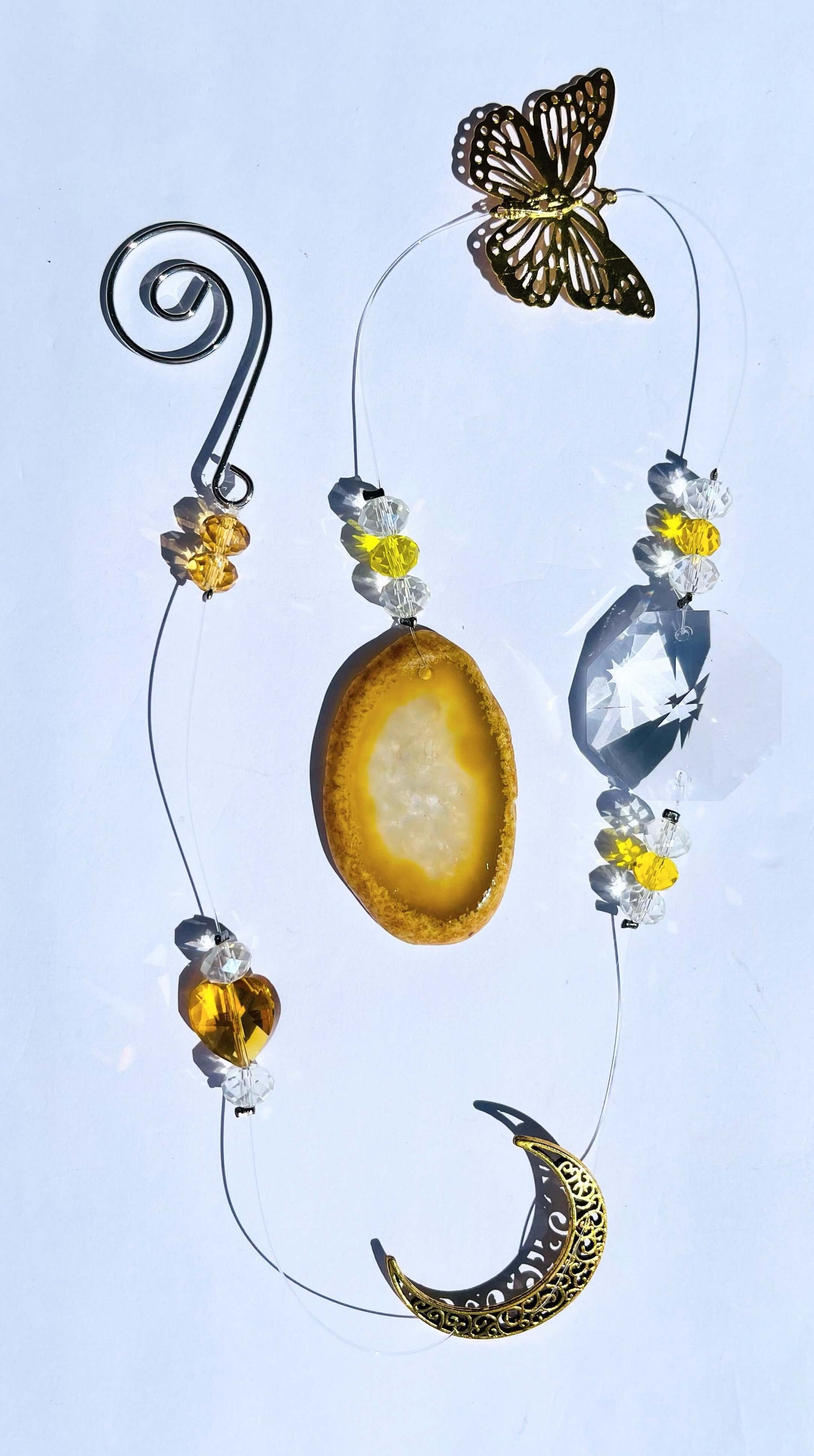 Crystal sun catcher with yellow agate and crescent moon charm on white background