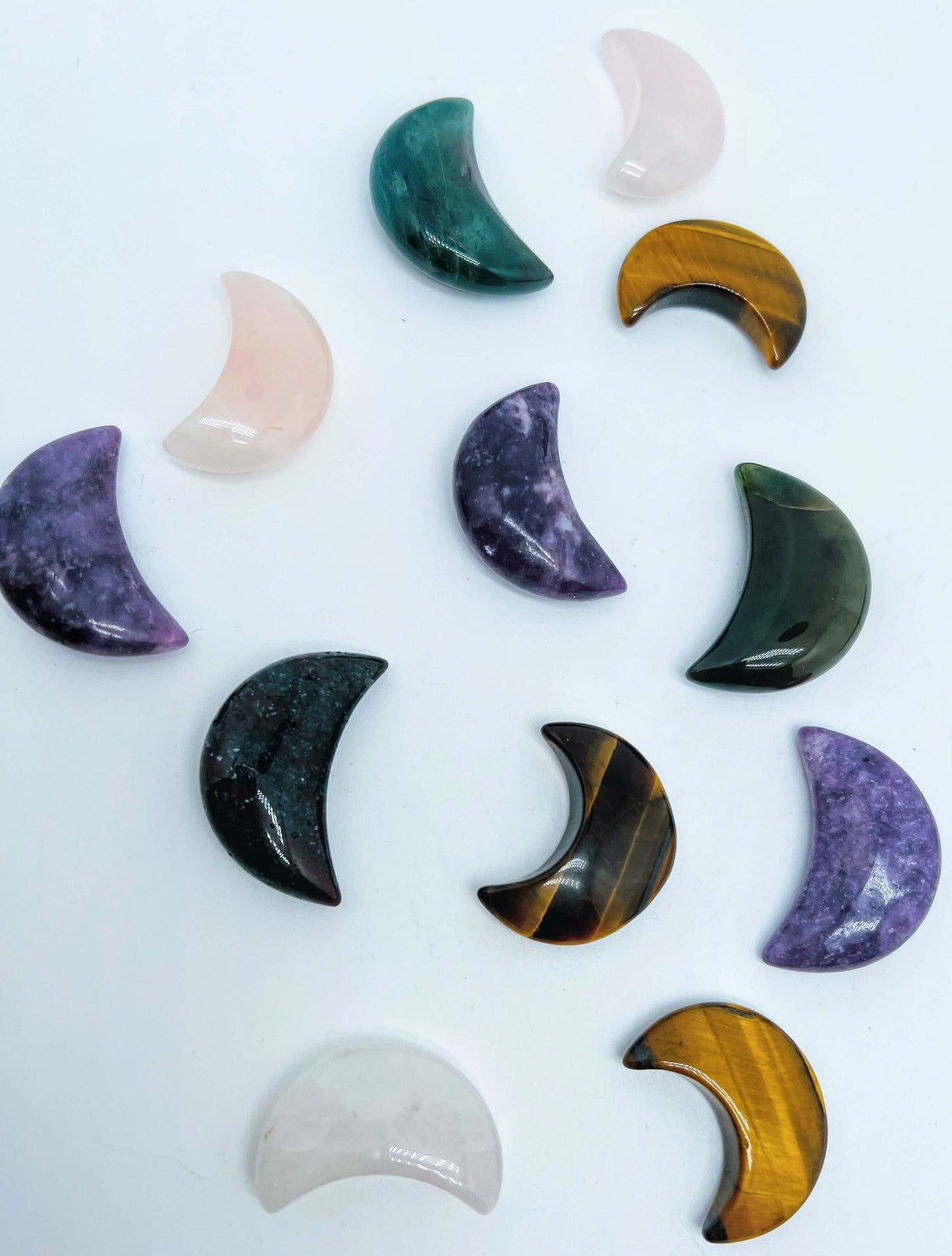 Several carved Crystal moons of different crystal stones on white background