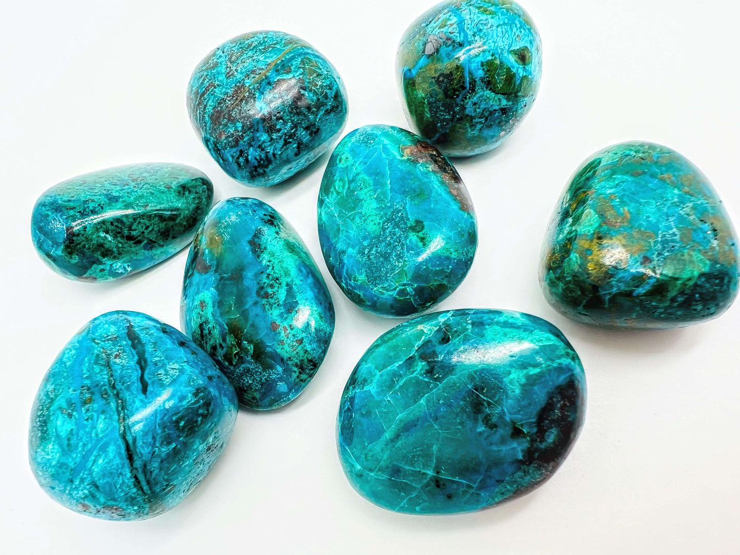 Several Chrysocolla tumbled stones on white background