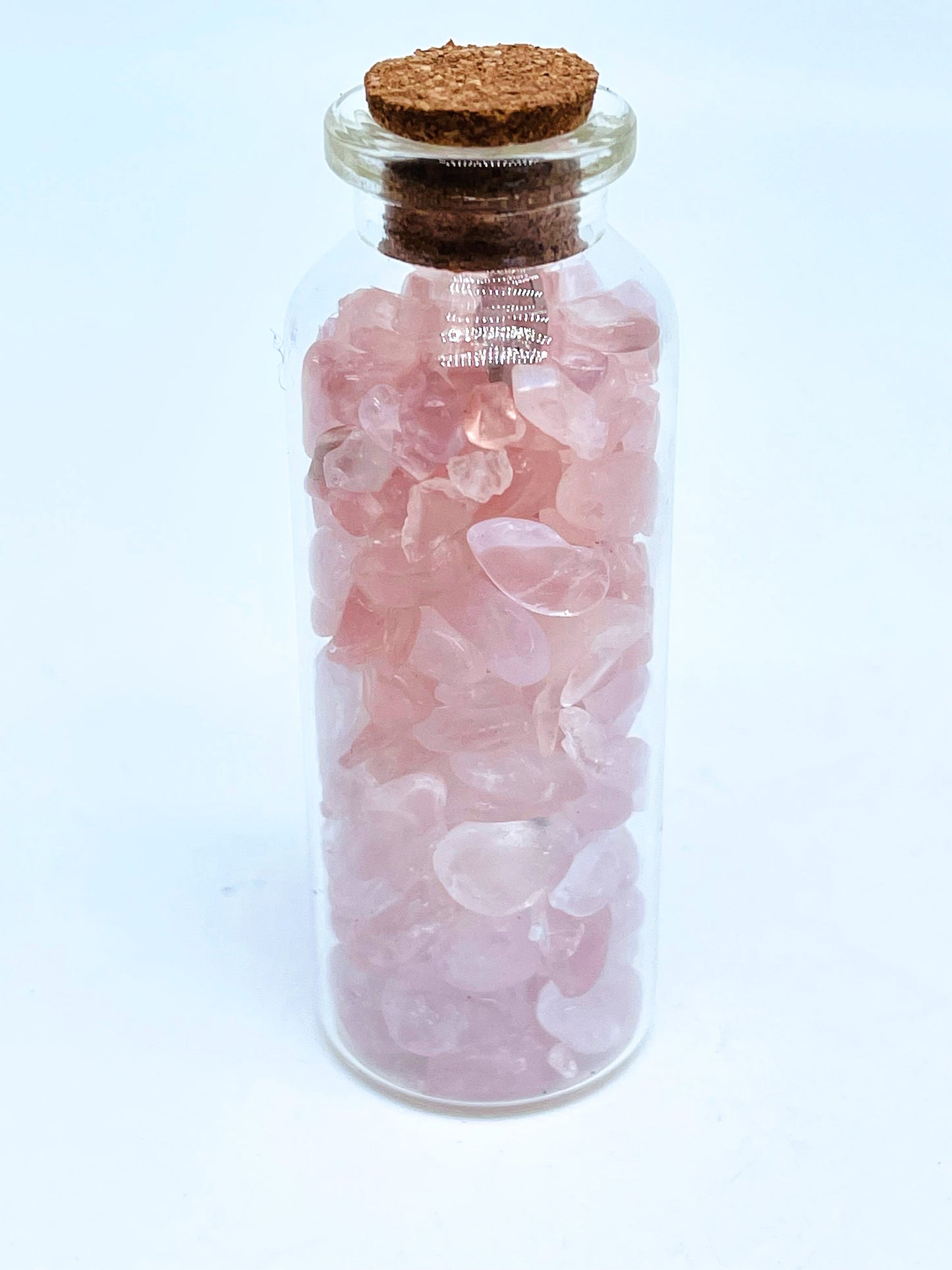 Rose quartz crystal chip bottle on white background