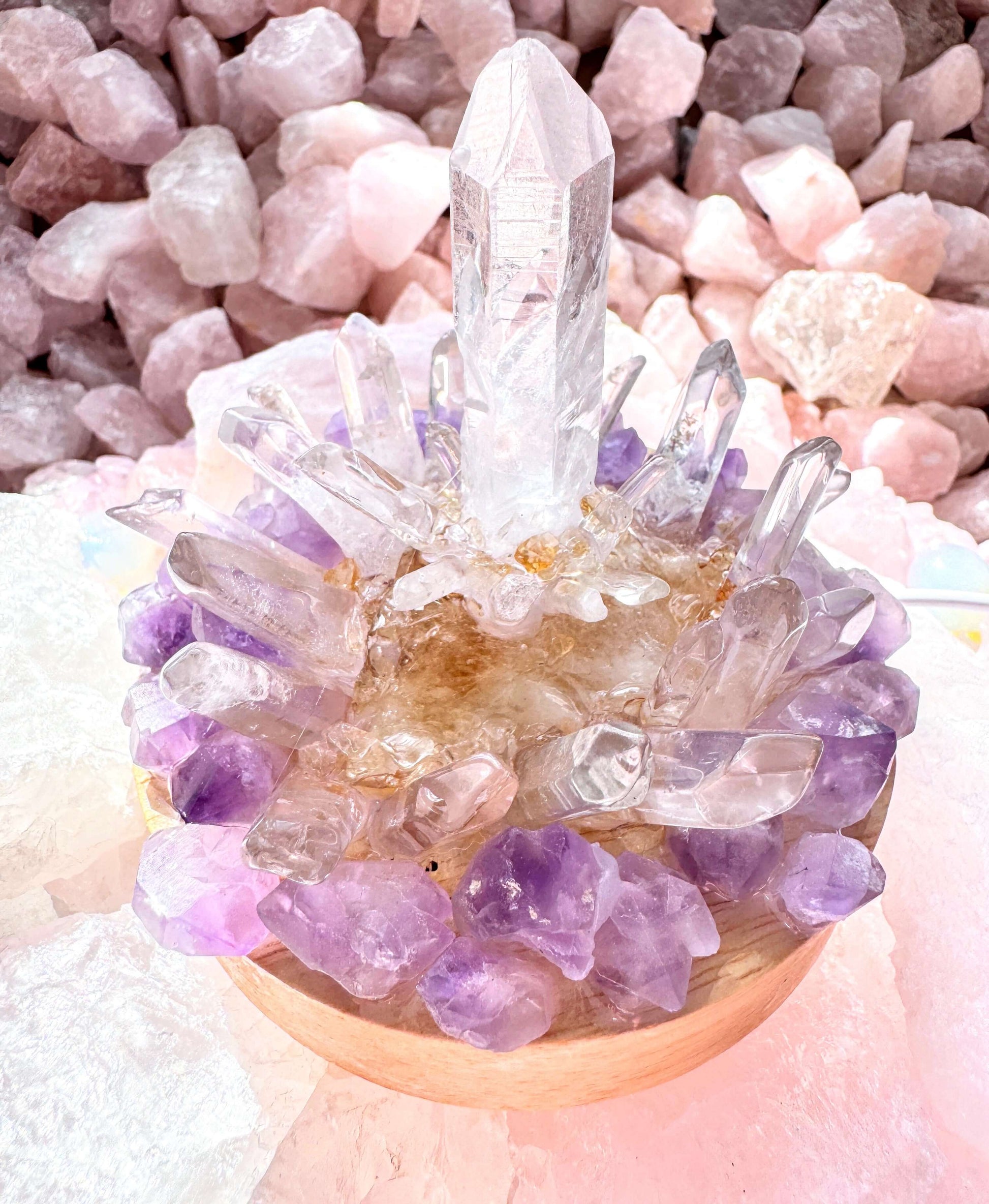 Crystal lamp with clear quartz and amethyst stones on wooden base, emitting warm light for clarity and balance.