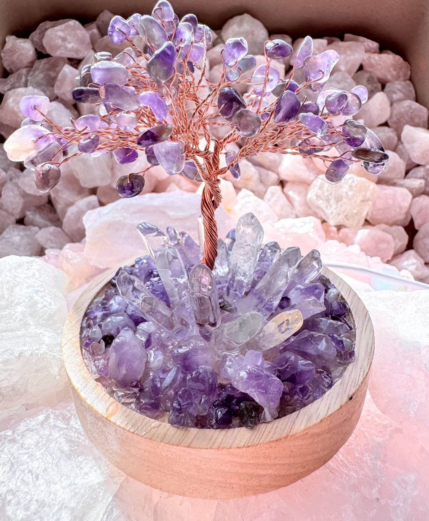 Crystal lamp featuring an amethyst tree with clear quartz points, wooden base, surrounded by purple amethyst chips for a radiant display.