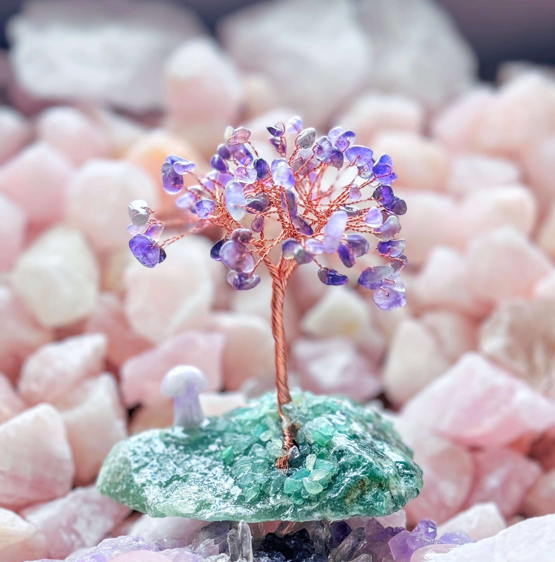 Handcrafted amethyst crystal tree on aventurine base with carved amethyst mushroom, surrounded by stones.