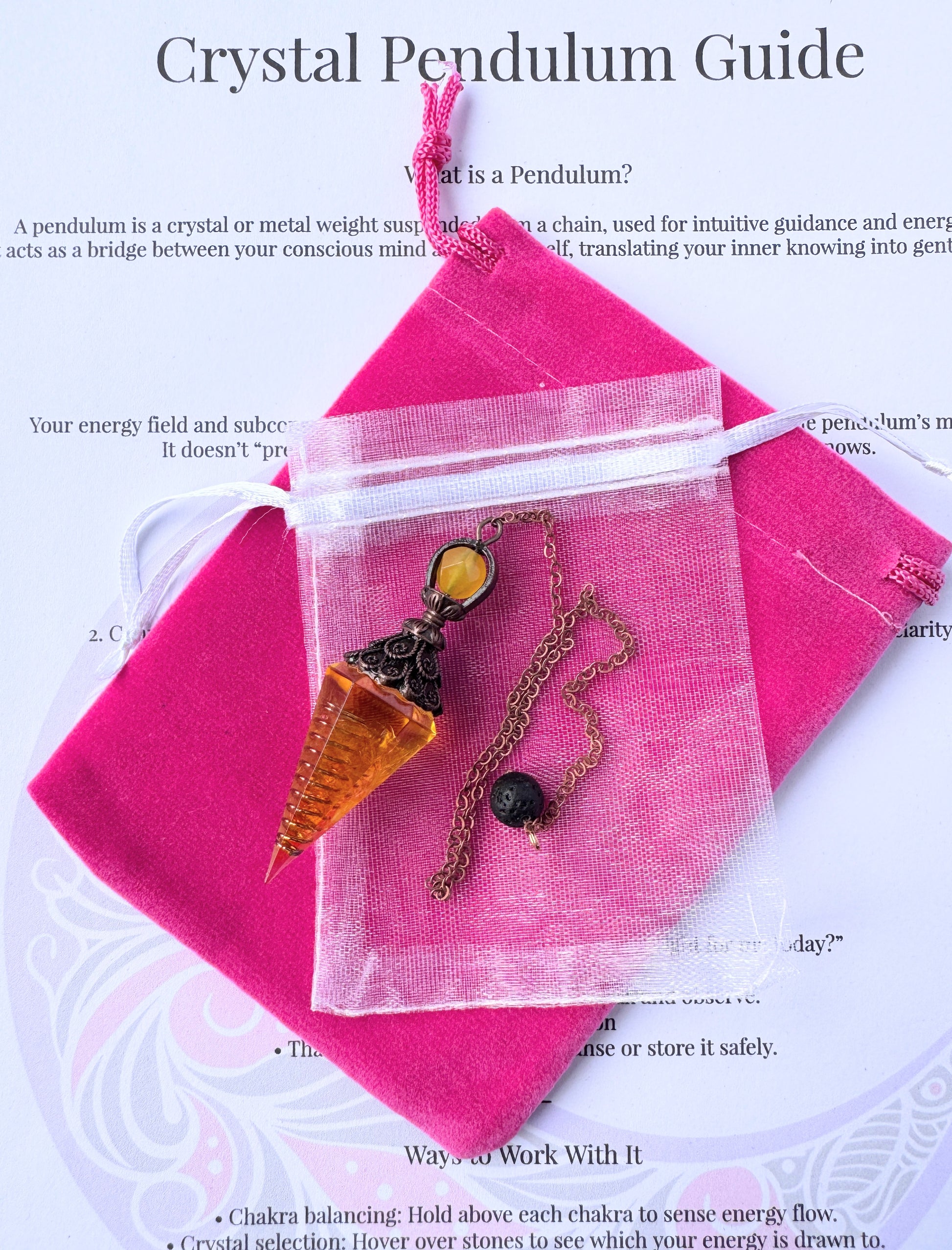 crystal pendulum with bronze chain and bead, displayed with pink pouch and printed pendulum guide