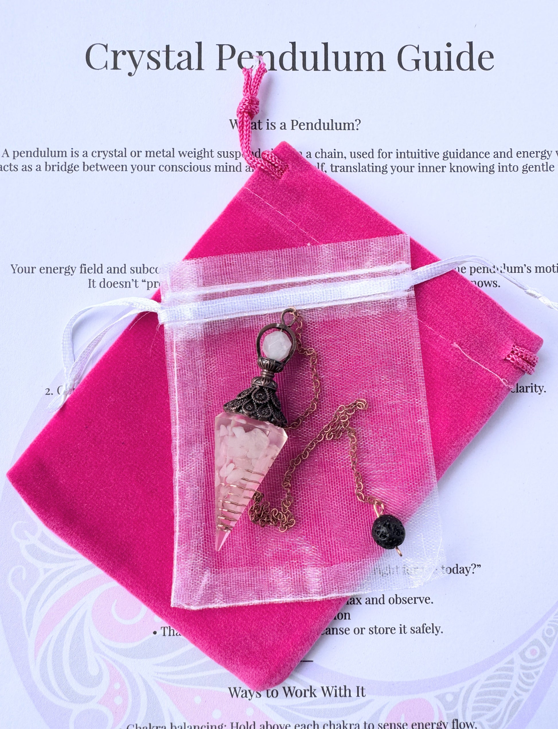  crystal pendulum with bronze chain and bead, displayed with pink pouch and printed pendulum guide