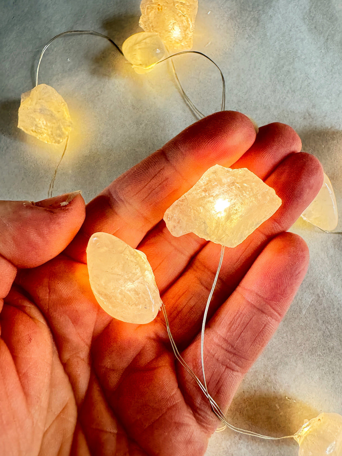 Crystal fairy lights glowing in hand with tumbled stones illuminating warm, soft light.