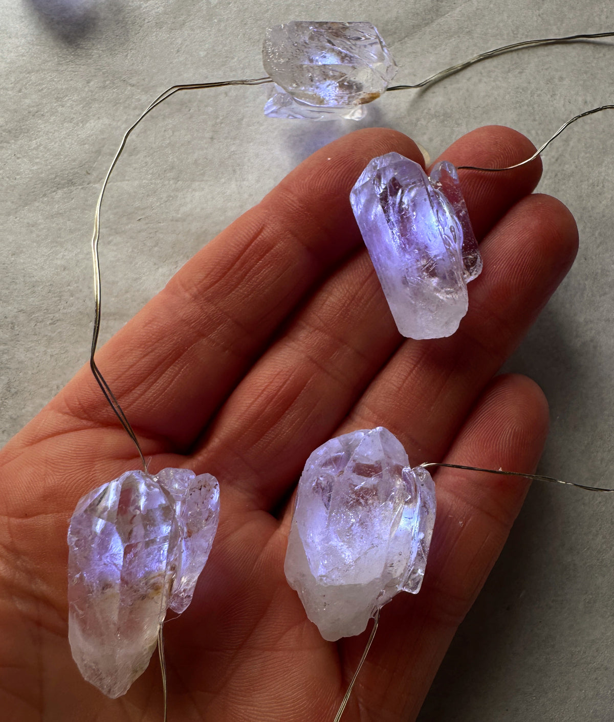 Crystal fairy lights featuring clear quartz crystals gently glowing in a person's hand.