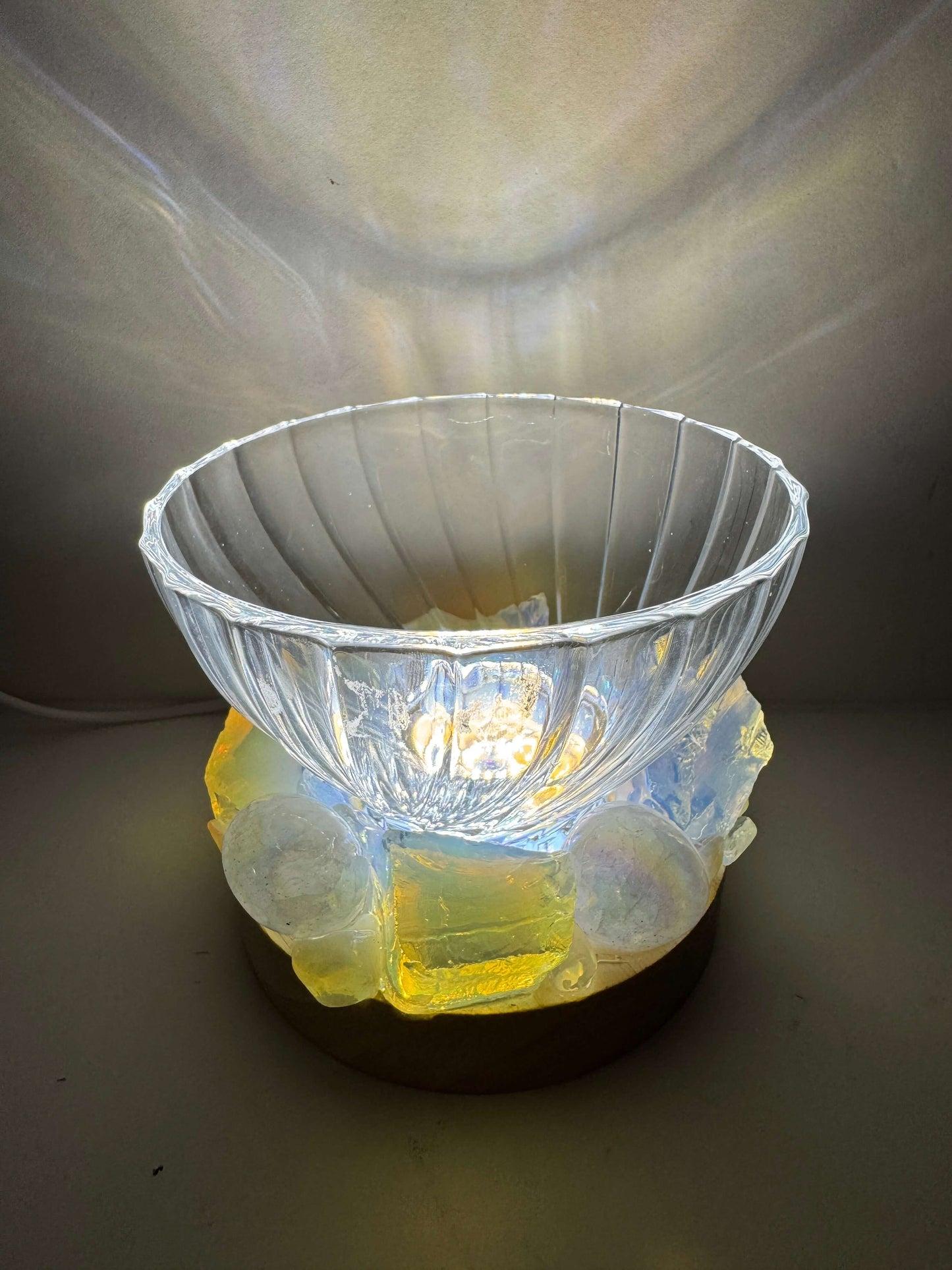 Opal Glow crystal light bowl with opalite and angel aura quartz on a wooden LED base, illuminated to showcase its iridescence.
