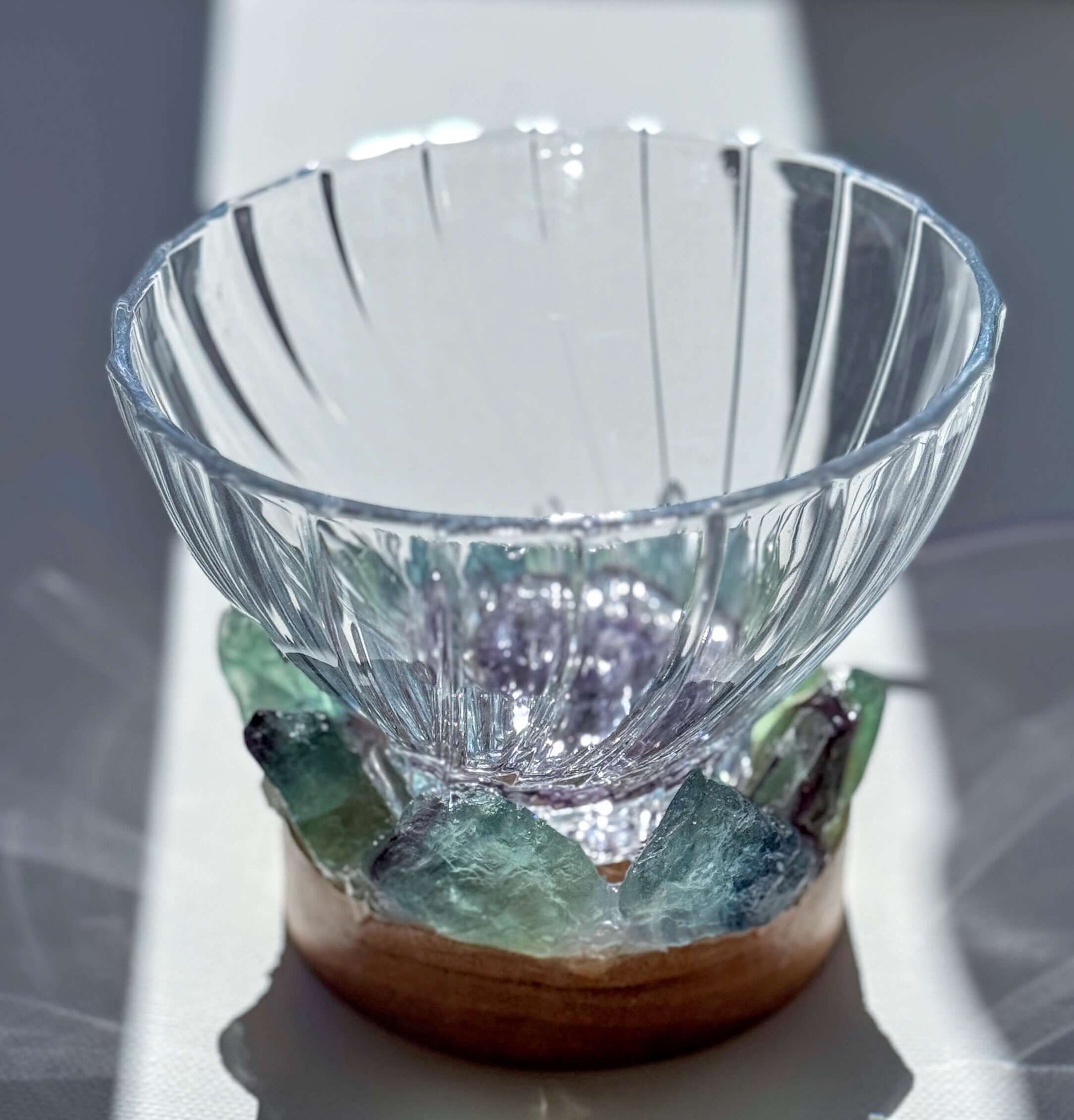 Northern light crystal light bowl with fluorite and clear quartz on wooden LED base, highlighting natural color variations.