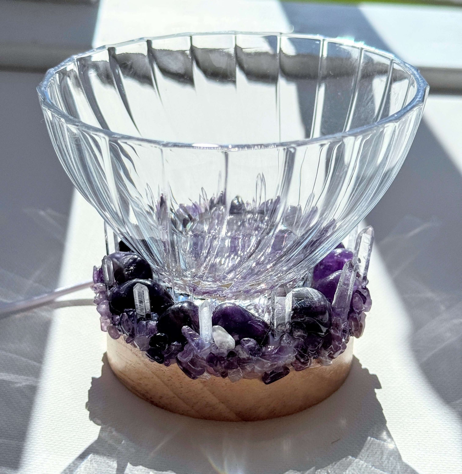 Twilight Calm Crystal light bowl with clear glass and amethyst on wooden LED base, emitting a soft glow.