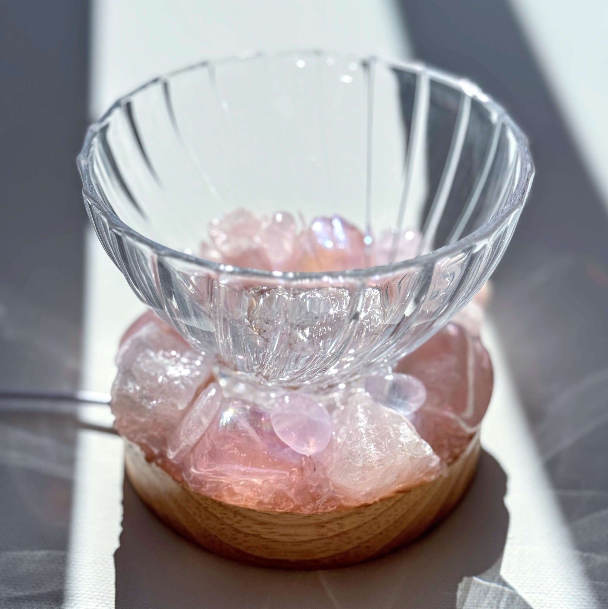 Rose Aura Crystal Light Bowl with rose quartz on wooden LED light base, illuminating the gentle pink and iridescent hues.