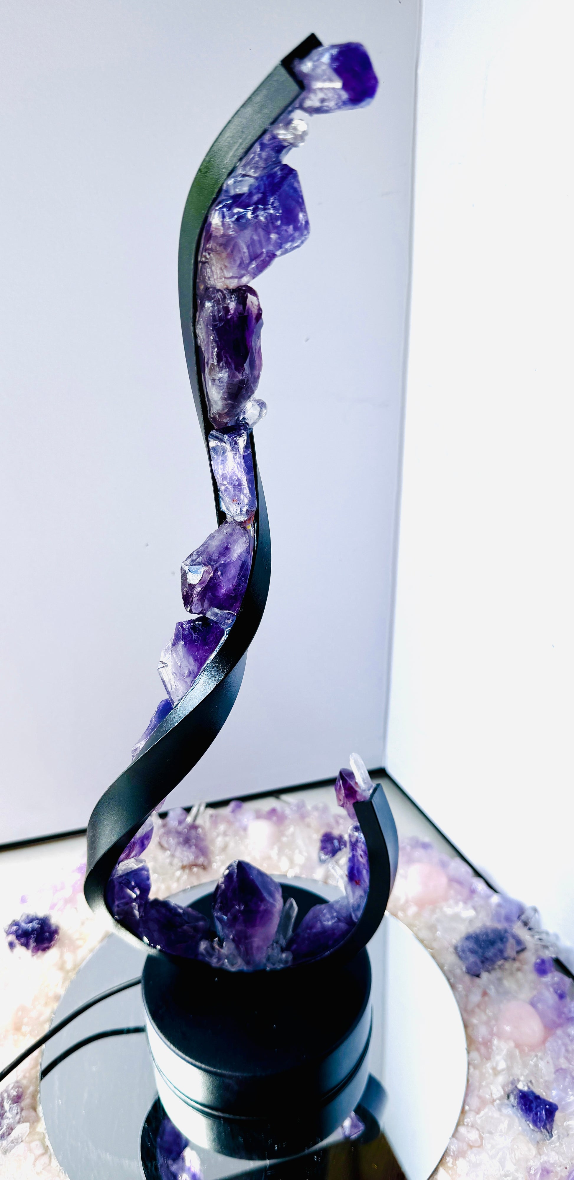 Amethyst crystal lamp with wave-shaped design and raw amethyst stones for calming and clarity on display.
