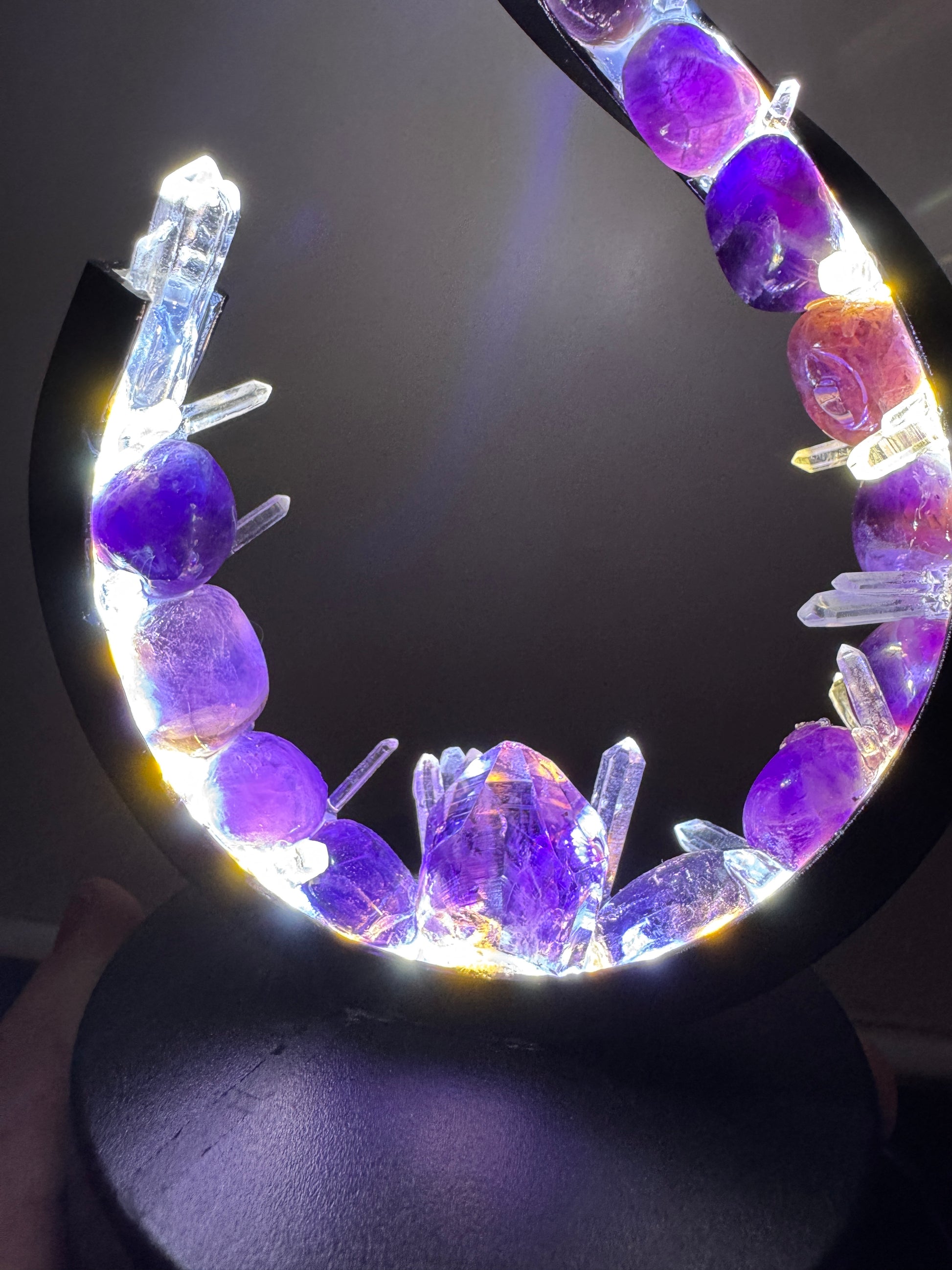 Crystal lamp "Amethyst Flow" with violet amethyst and clear quartz on a wave-shaped frame, creating a calming luminous effect.