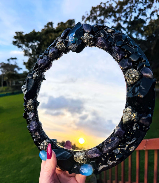 Handmade crystal mirror with gemstone border reflecting natural light