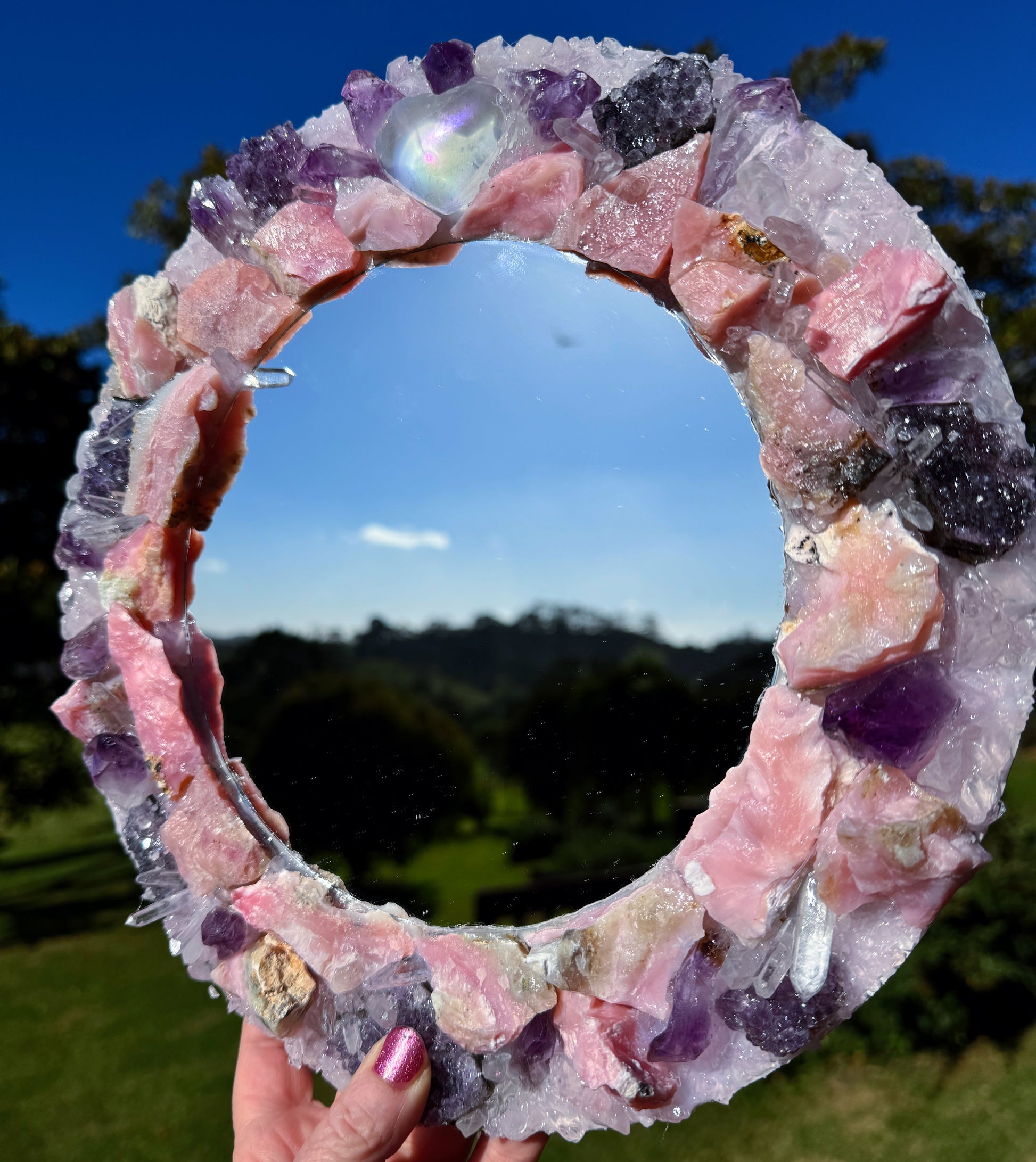 Angel Aura Love Crystal Mirror 28cm with Pink Aura Quartz, Rose Quartz, Amethyst, and Clear Quartz in a luminous outdoor setting
