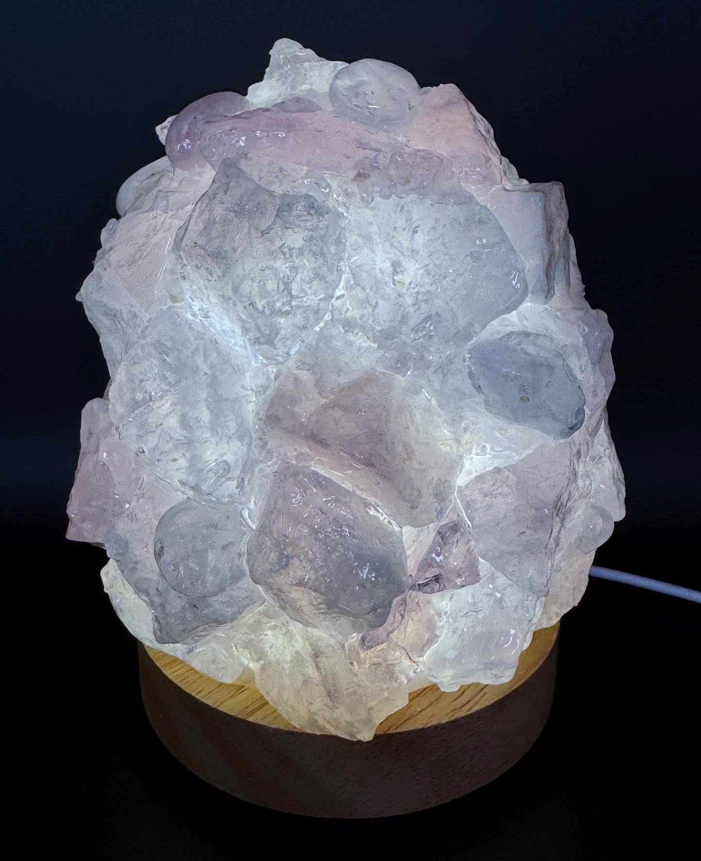 Rose Quartz Crystal Lamp with rough pink stones on a wooden base, 10cm base, 14cm height, softly glowing in the dark.