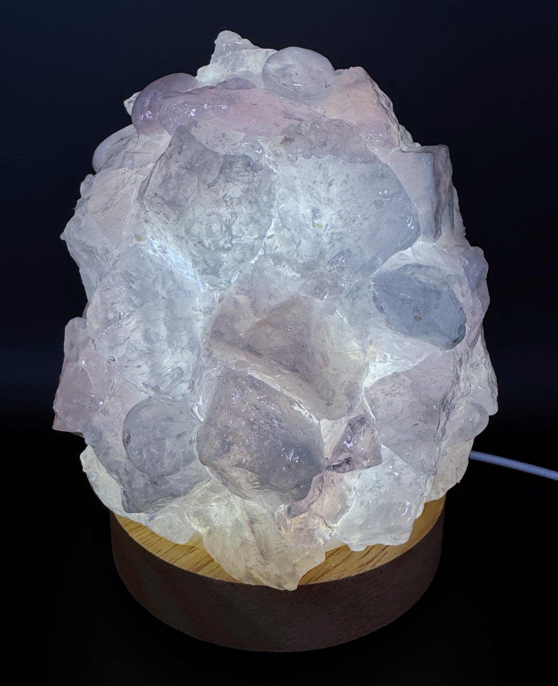 Rose Quartz Crystal Lamp with rough pink stones on a wooden base, 10cm base, 14cm height, softly glowing in the dark.