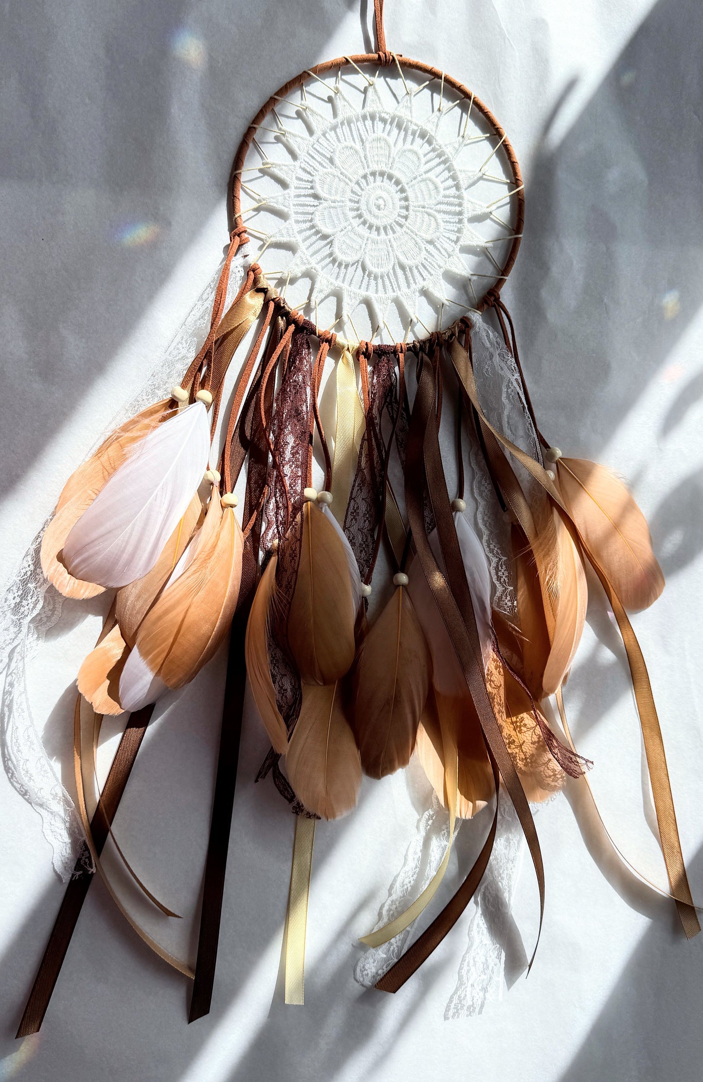 Natural tones dream catcher featuring soft earthy shades and flowing ribbons, perfect for adding texture to any space.