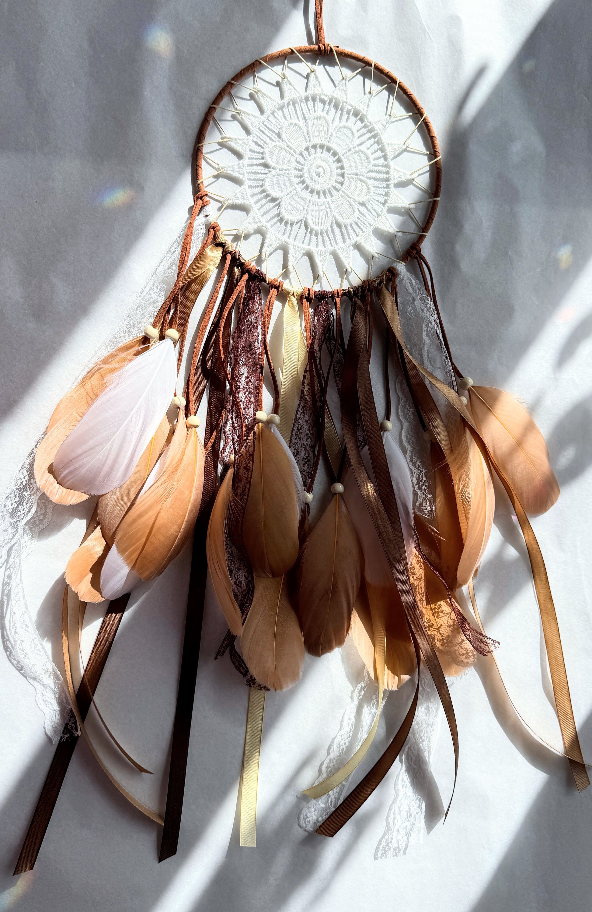 Natural tones dream catcher featuring soft earthy shades and flowing ribbons, perfect for adding texture to any space.