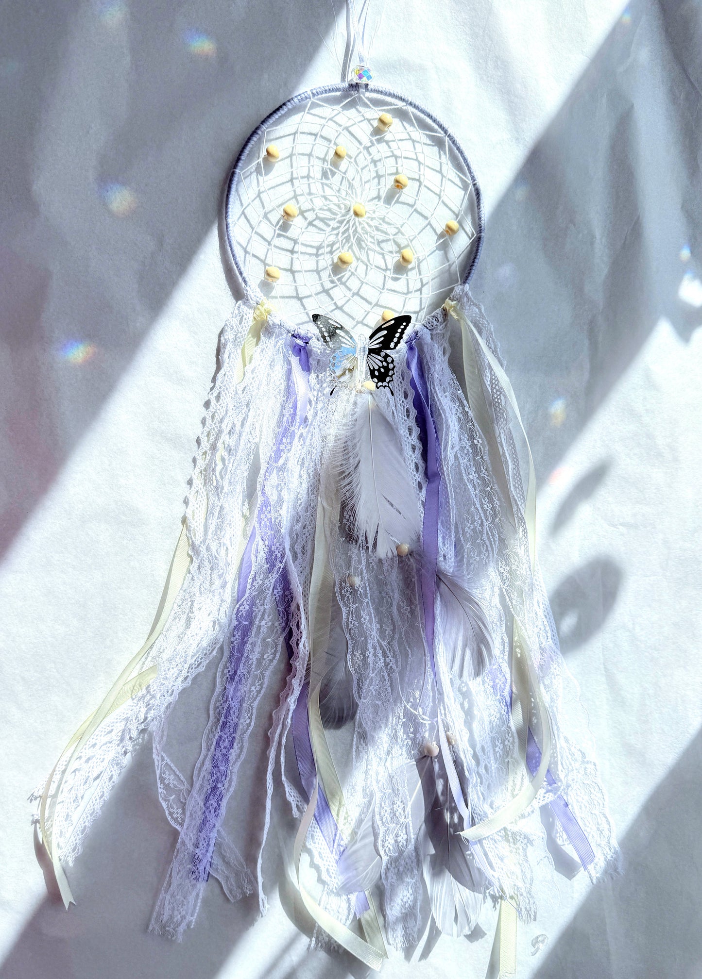 Lavender dream catcher with lace, ribbons, and feathers in lilac and white tones, bringing calm energy to your space.