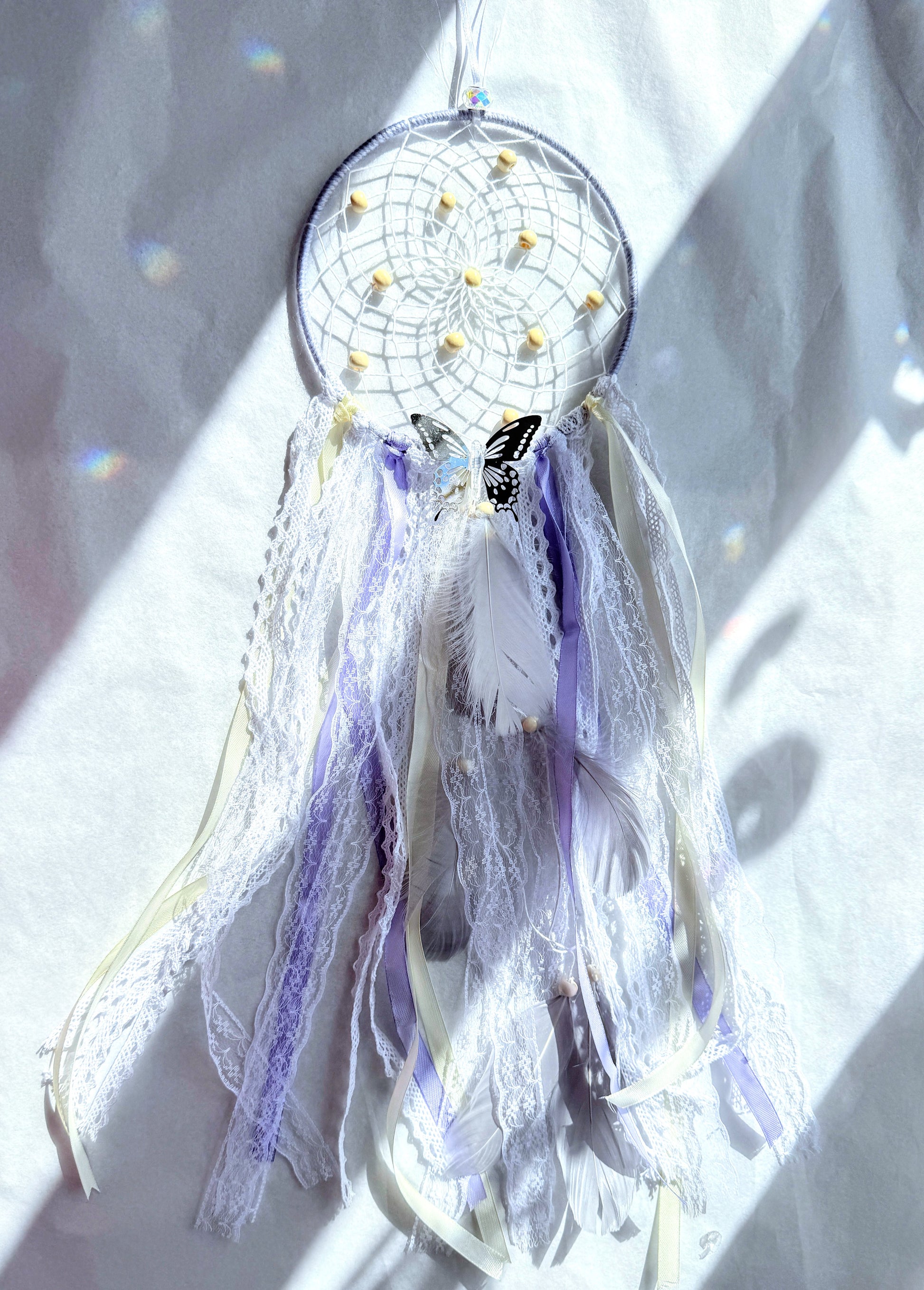 Lavender dream catcher with lace, ribbons, and feathers in lilac and white tones, bringing calm energy to your space.