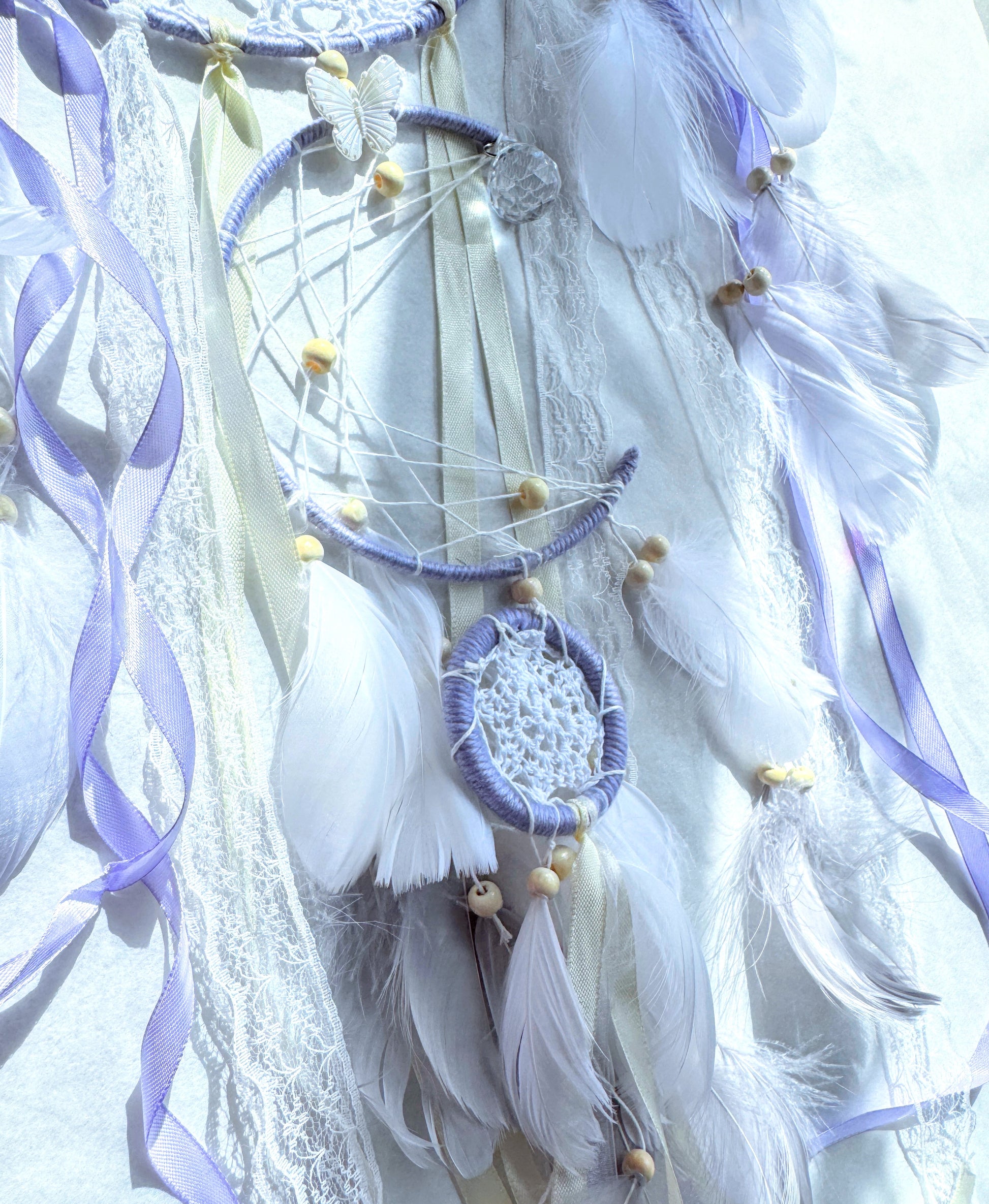 Large lavender dream catcher with soft feathers, ribbons, and lace accents for calming energy.