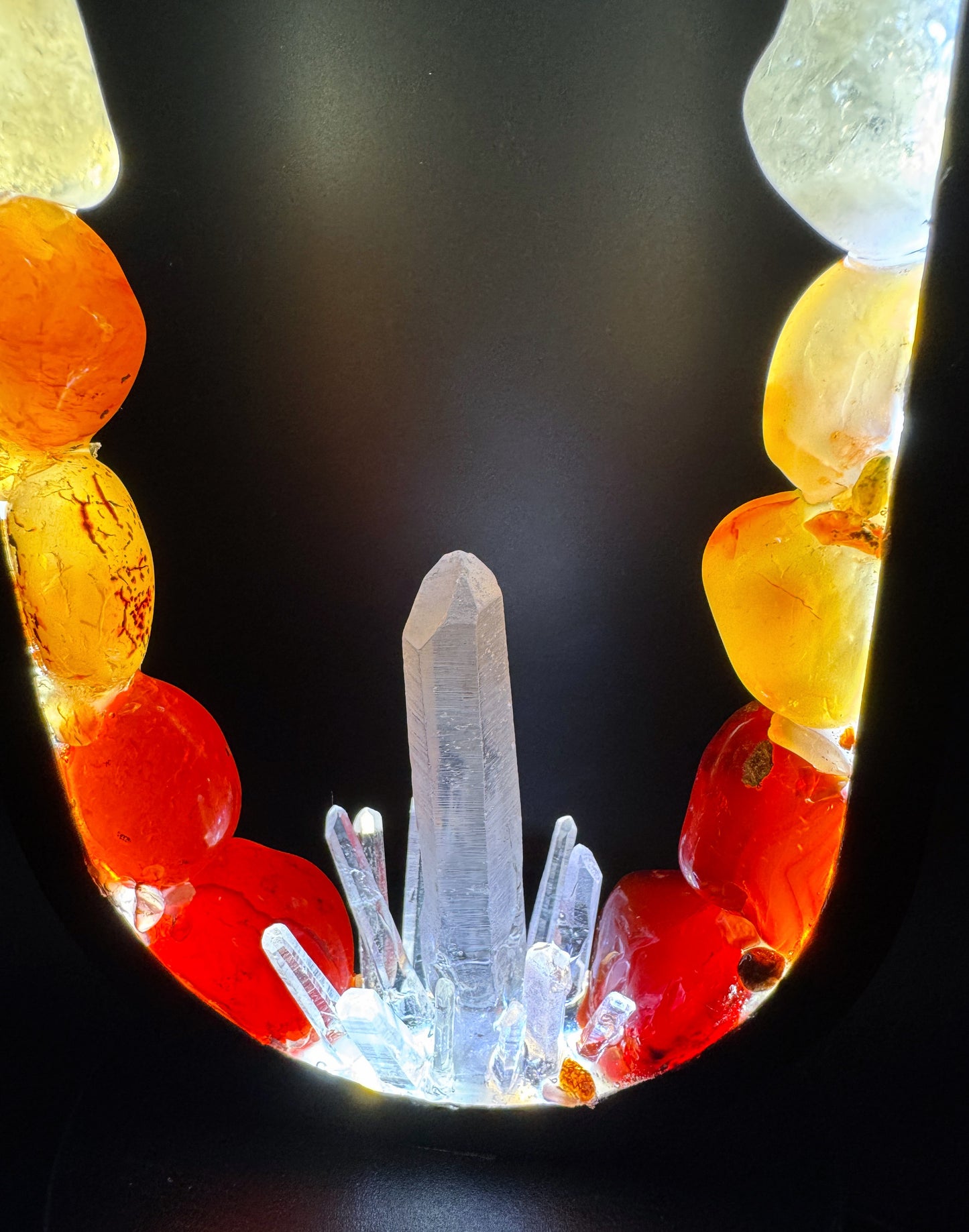 Crystal lamp featuring polished stones in rainbow colors with a central quartz point illuminating the design.