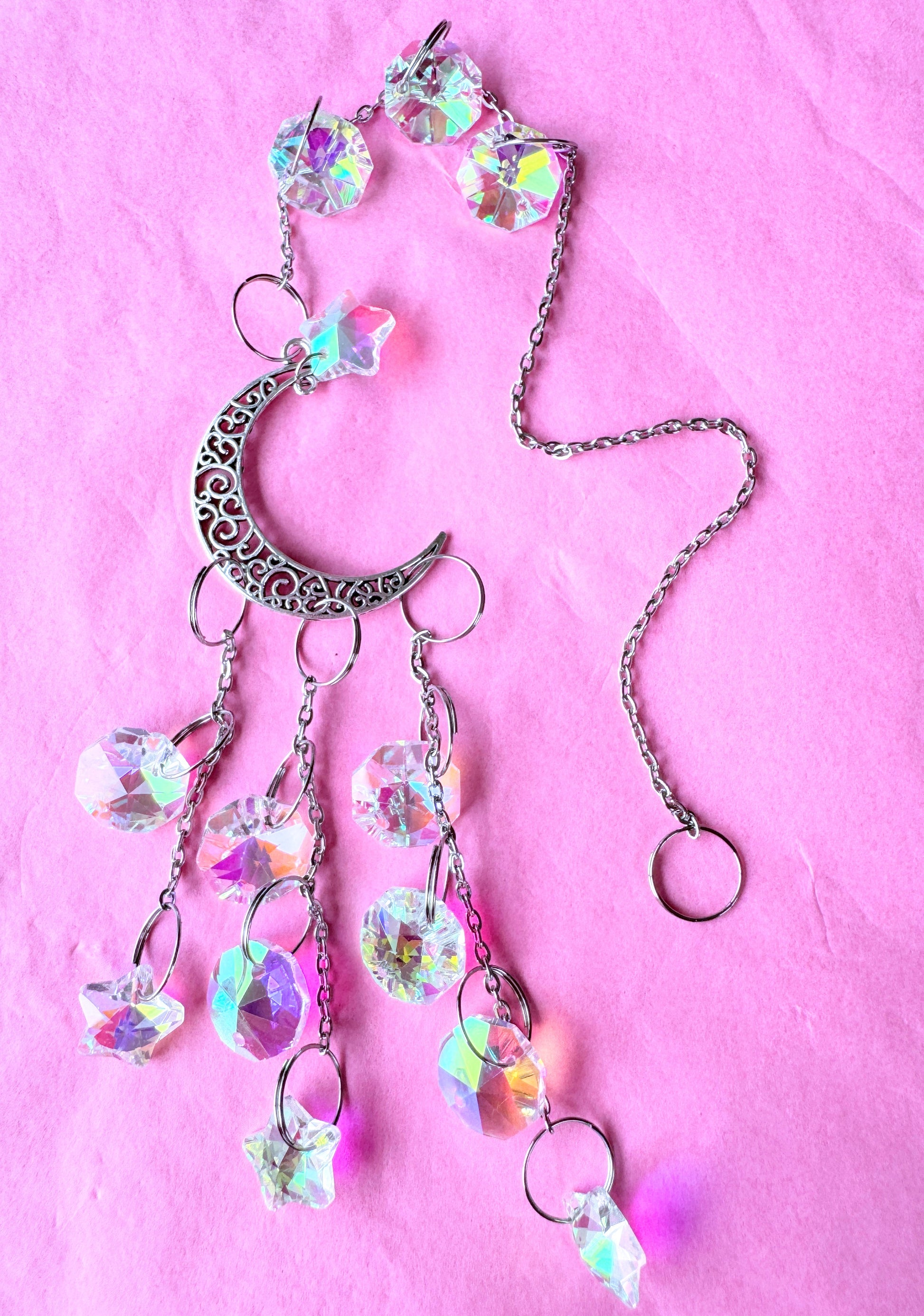 Iridescent cascade sun catcher Lying on pink background 