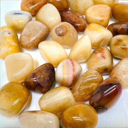 Golden healer tumbled stones on white surface. 