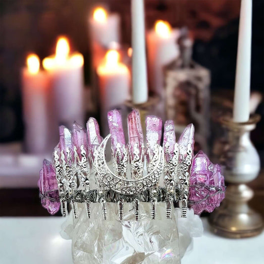 Pink aura quarts crystal crown on white surface with candles in background.