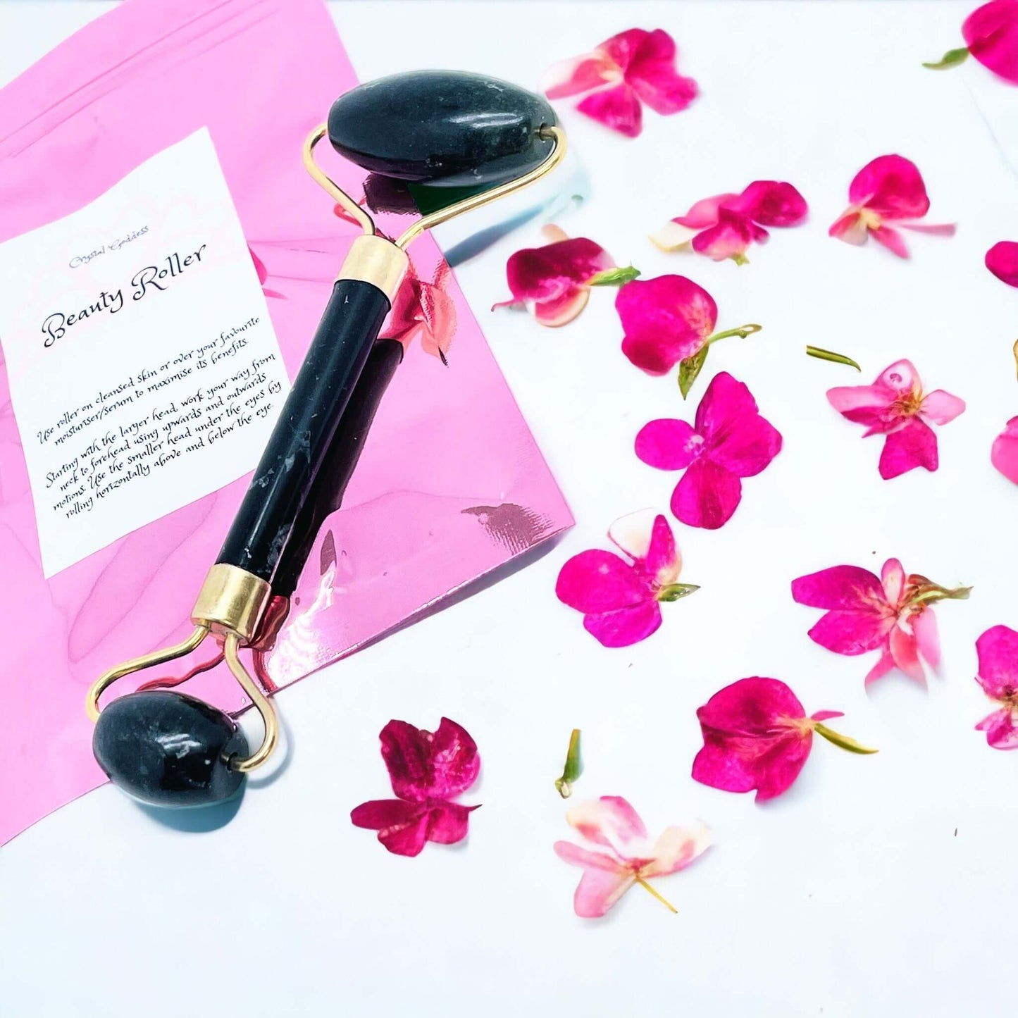 Black Stone beauty face roller with petals on white background 