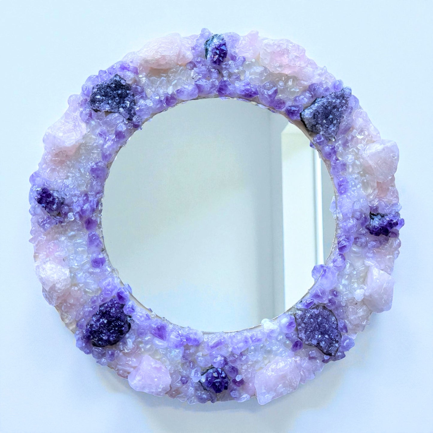 Crystal Mirror “Amethyst Bloom” with 28cm frame, featuring a blend of amethyst flowers, clusters, and rose quartz in a violet-pink palette.