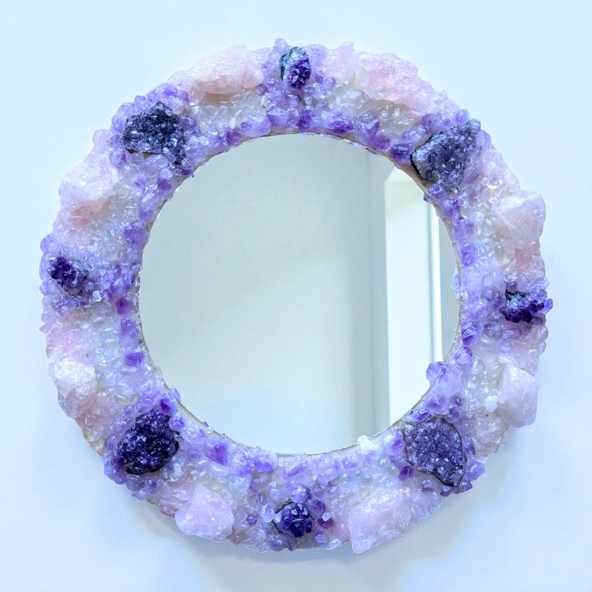 Crystal Mirror “Amethyst Bloom” with 28cm frame, featuring a blend of amethyst flowers, clusters, and rose quartz in a violet-pink palette.