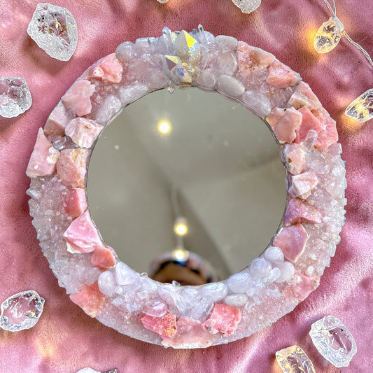 Angel Aura Crystal Mirror 28cm featuring Pink Opal, Rose Quartz, Clear Quartz, and Angel Aura Quartz cluster on pink fabric.