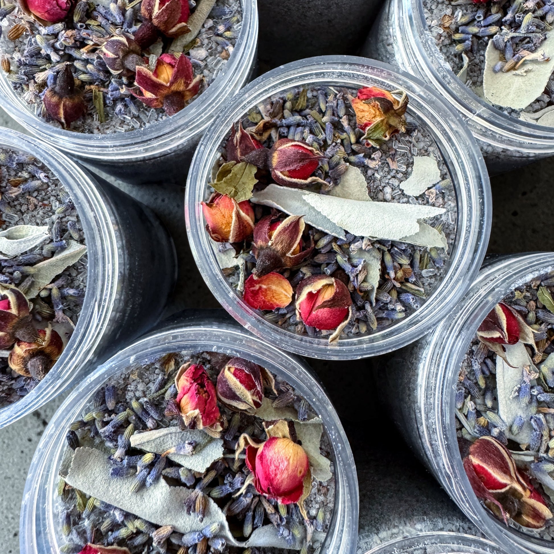 Close-up of Energy Cleansing Bath Salts in jars with dried flowers and herbs.