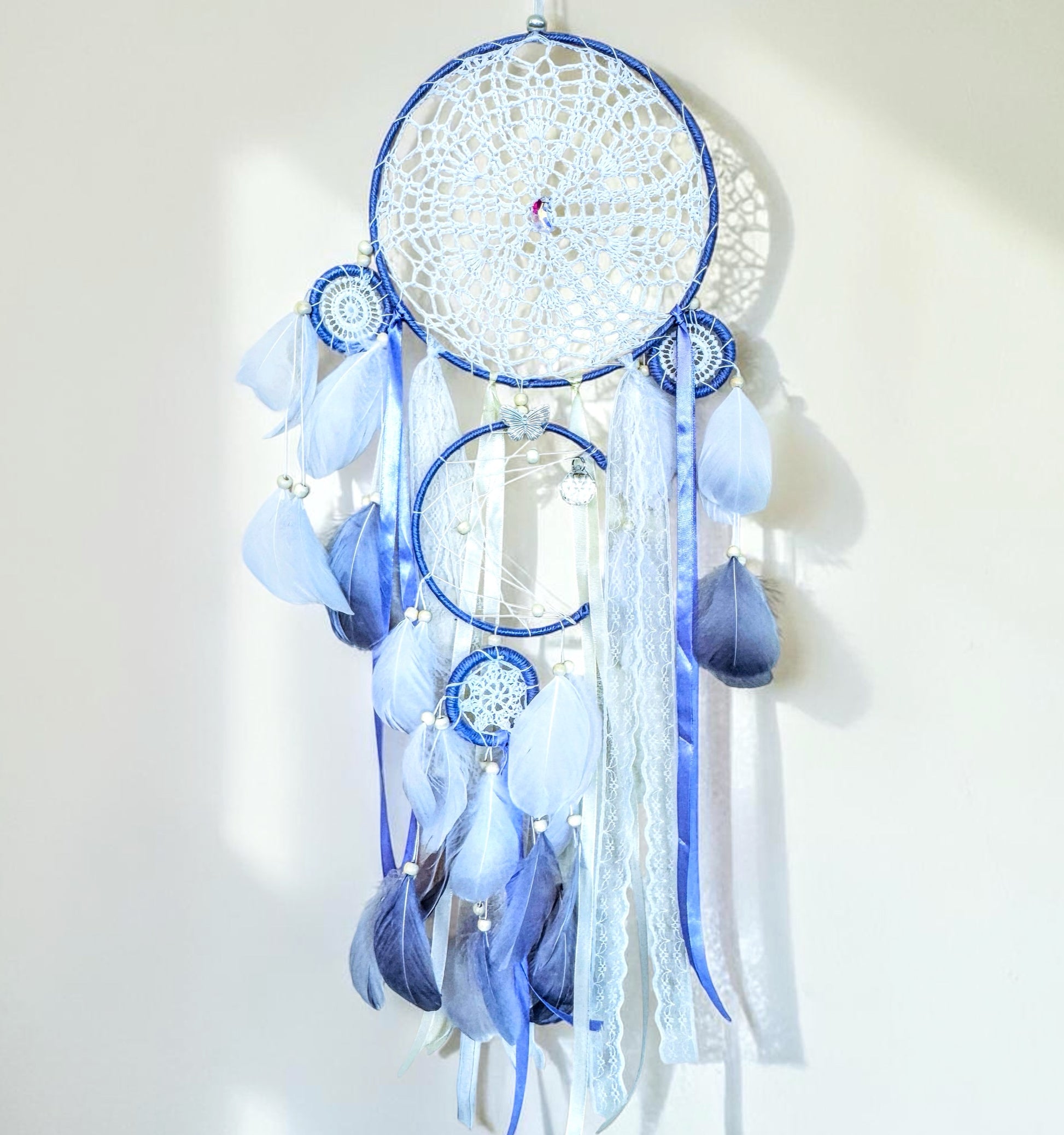 Large lavender dream catcher with delicate woven web, ribbons, and feathers in soft pastel tones.